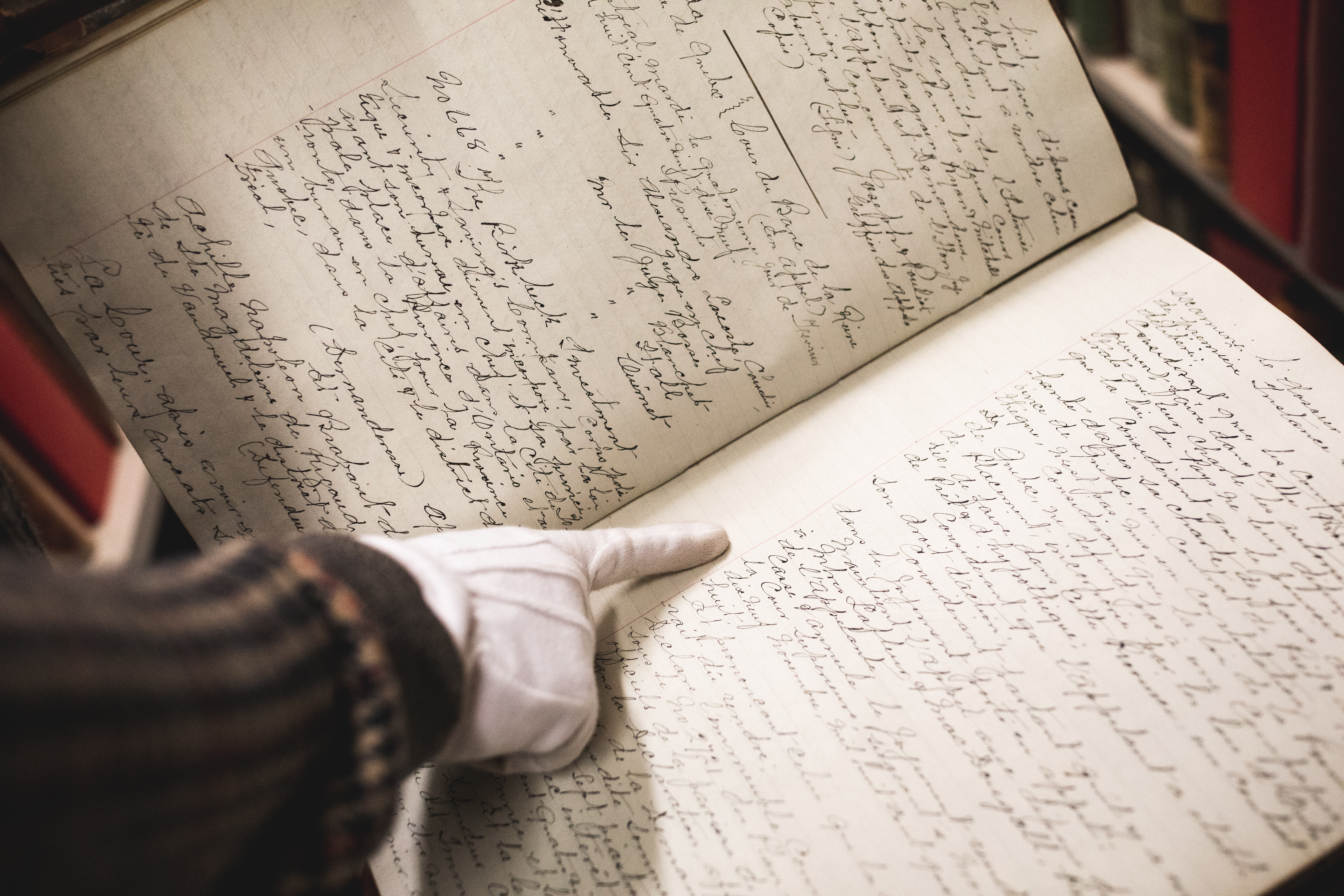 Une main pointe un texte dans un registre manuscrit