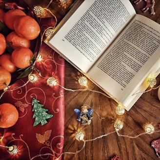 Livre ouvert entouré de guirlandes, de chandelles, d'oranges et de décorations de Noël