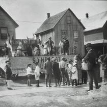 Des hommes, femmes et enfants près d'un char allégorique pour le défilé de la fête du Travail.