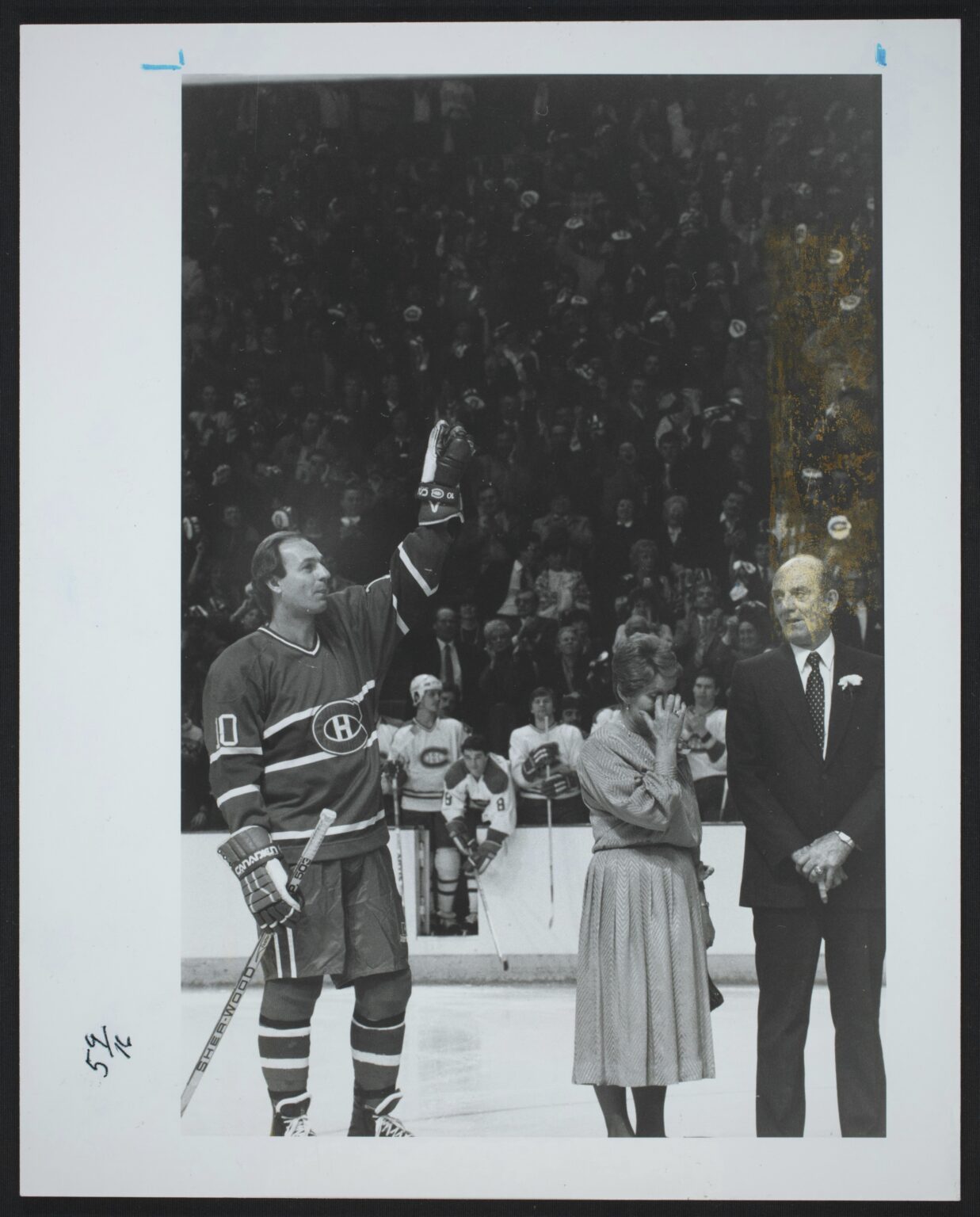 Le 16 février 1985, l’idole du Canadien de Montréal salue la foule au Forum au cours de la cérémonie du retrait de son chandail, le numéro 10. On le voit aux côtés de ses parents, émus et fiers.