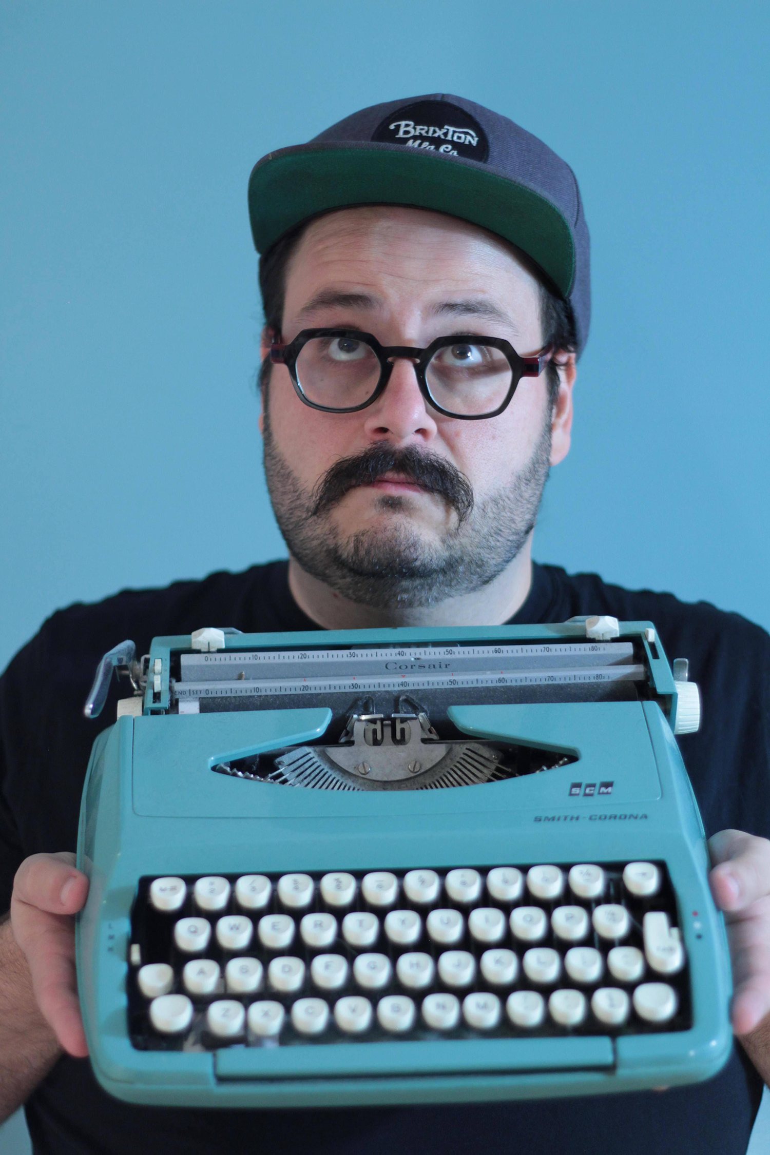 Un jeune homme tenant une machine à écrire.
