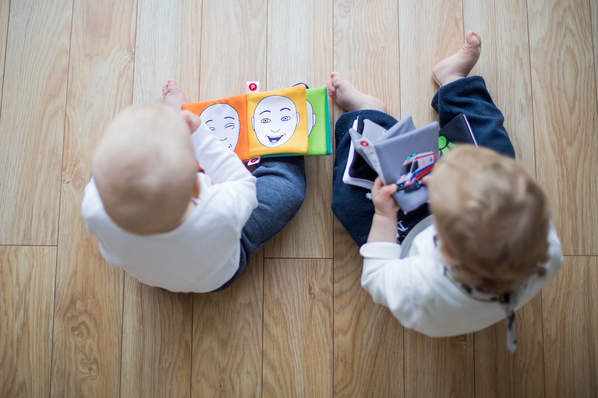 Deux jeunes enfants assis par terre regardent des livres.