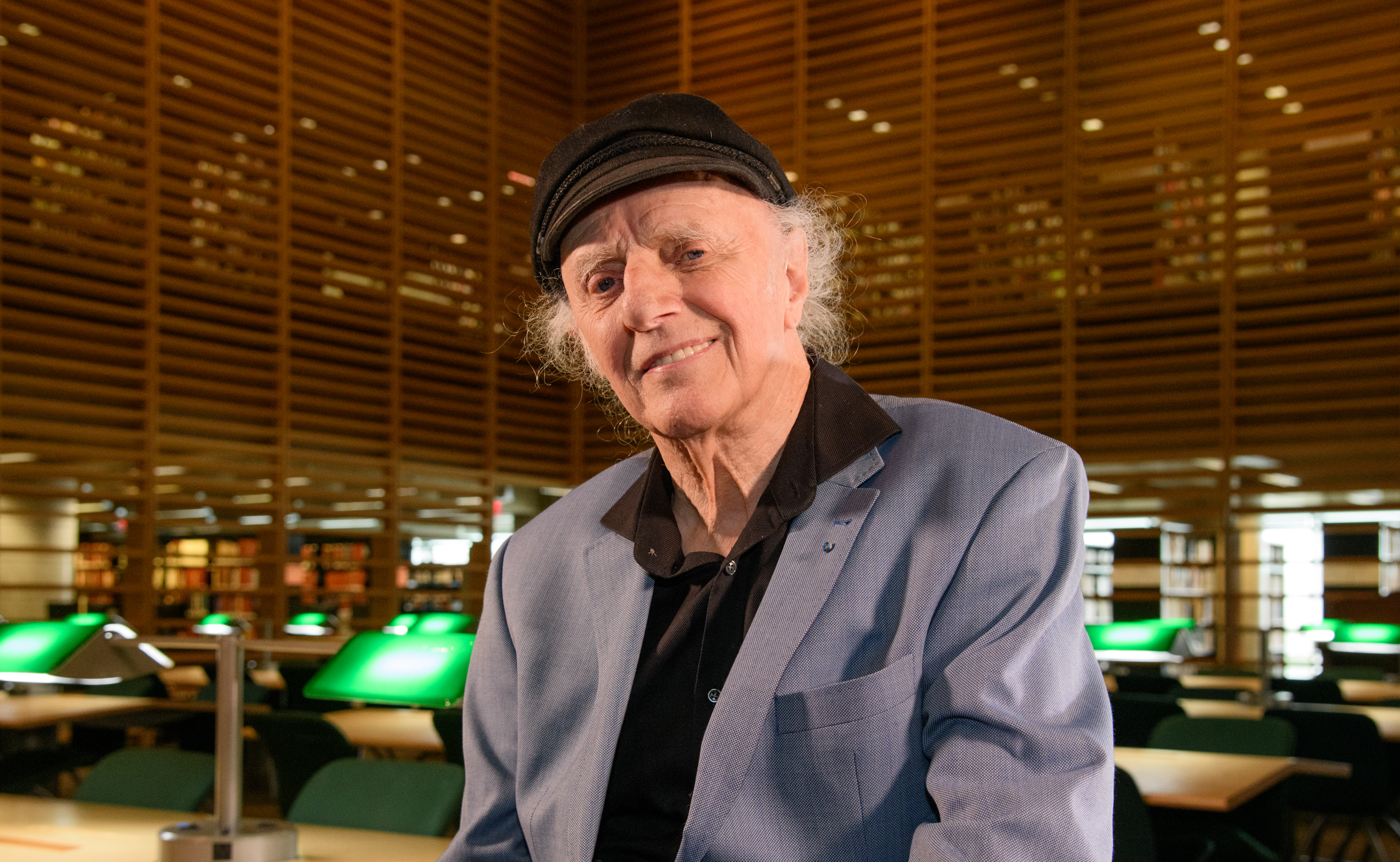 Gilles Vigneault souriant à la caméra dans les Chambres de bois de la Bibliothèque nationale au cœur de la Grande Bibliothèque