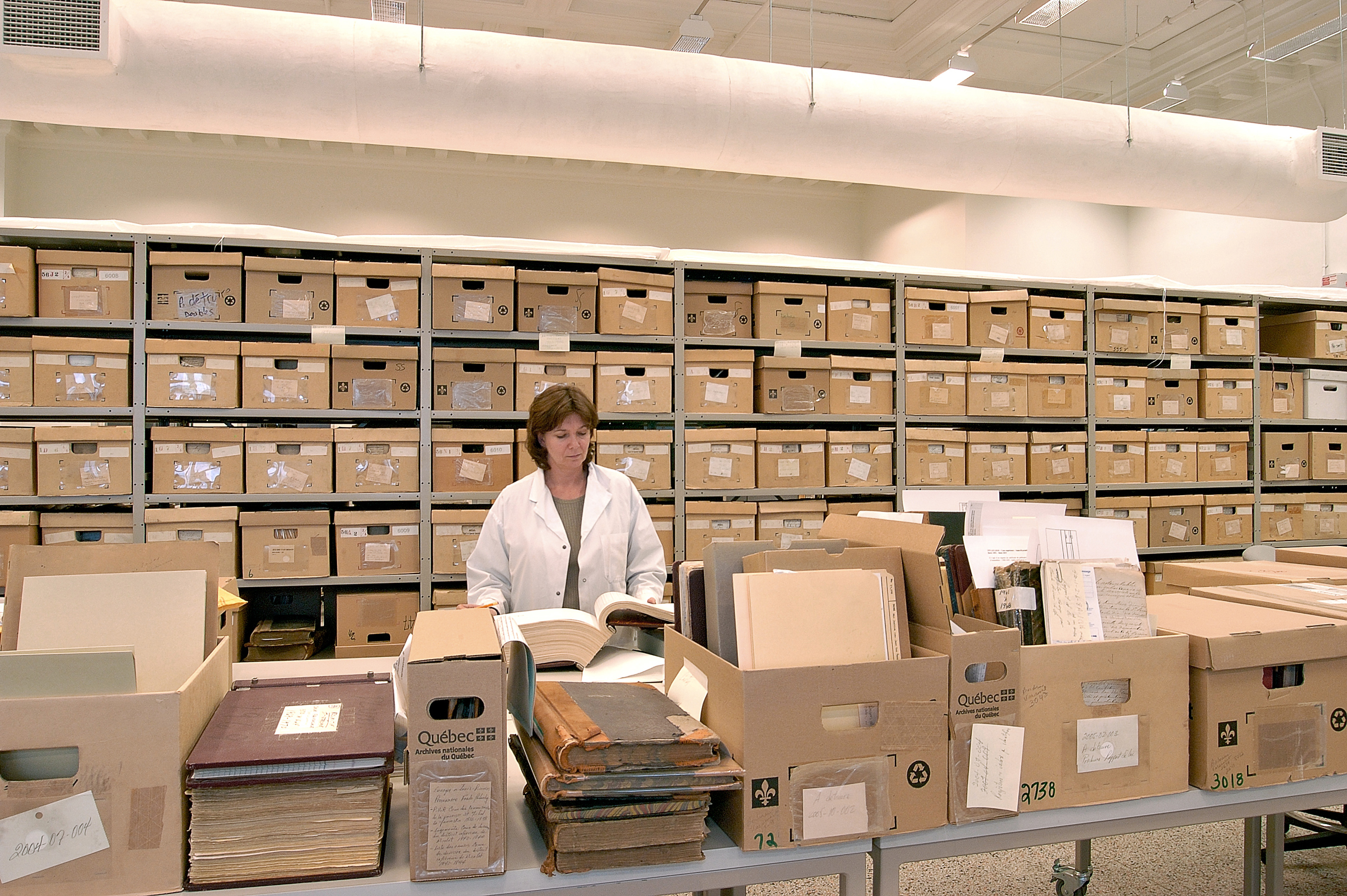 Une Employée de BAnQ entourée de boîtes travaille au traitement d'archives 