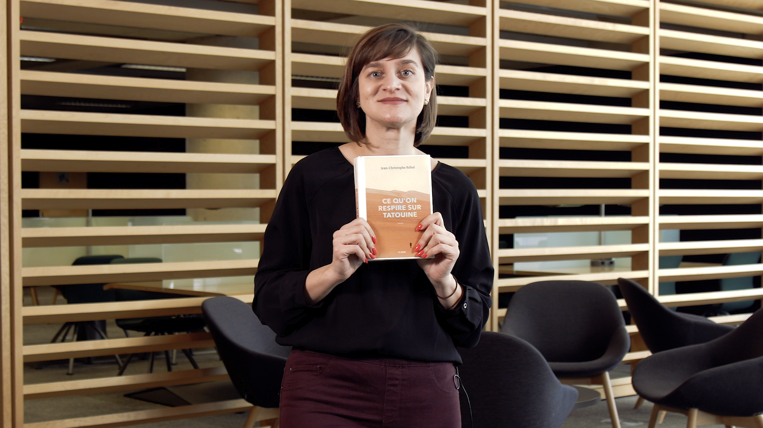 Femme tenant le livre «Ce qu'on respire sur Tatouine».