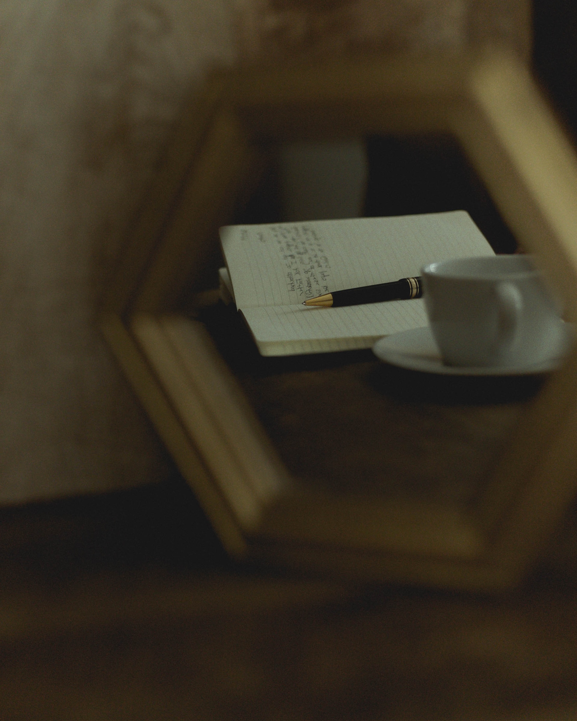 Reflet dans un miroir d'une cahier, d'un stylo et d'une tasse à café.