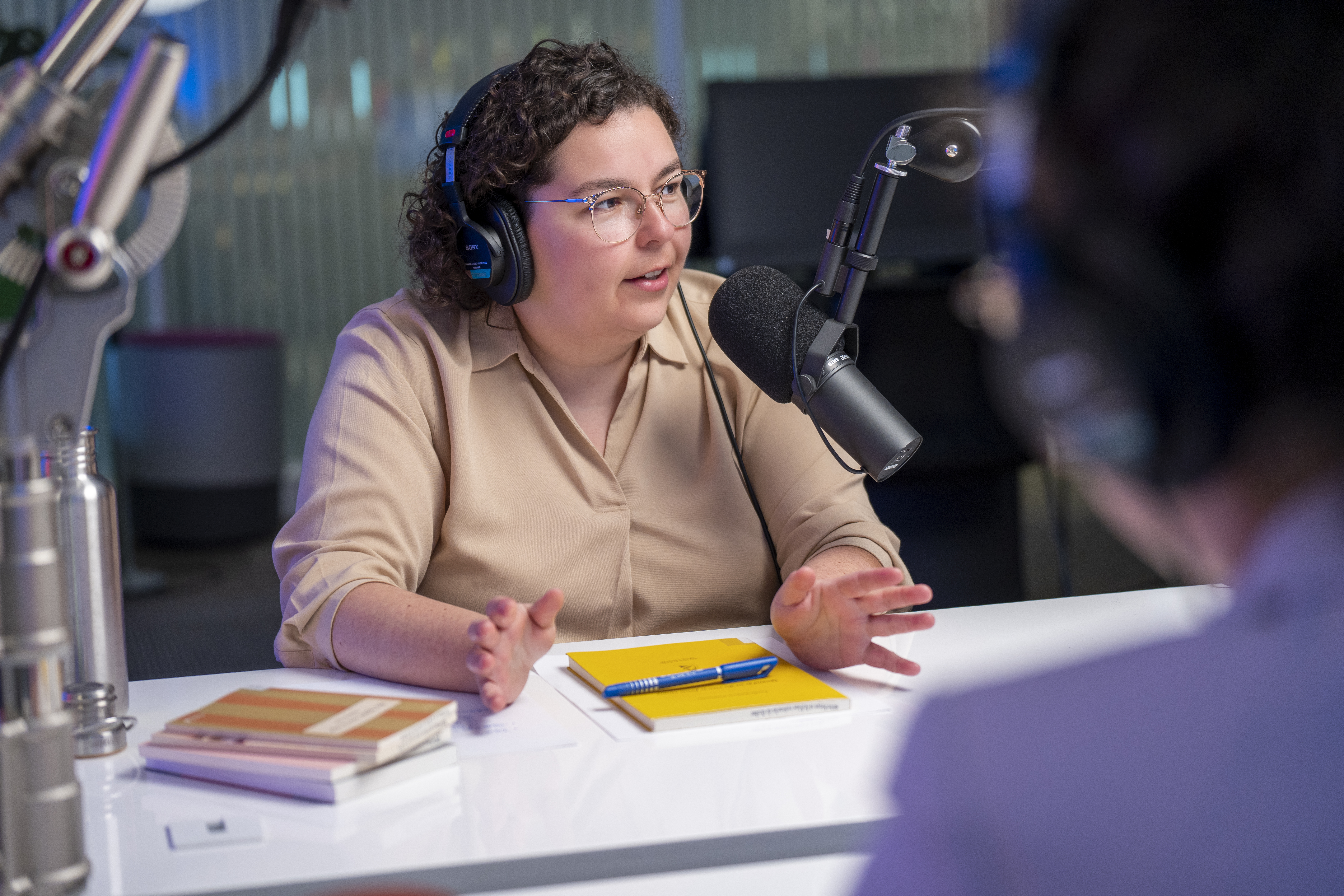 Marie-Ève derrière le micro et entourée de livres lors de l'enregistrement du balado "Signets au féminin"