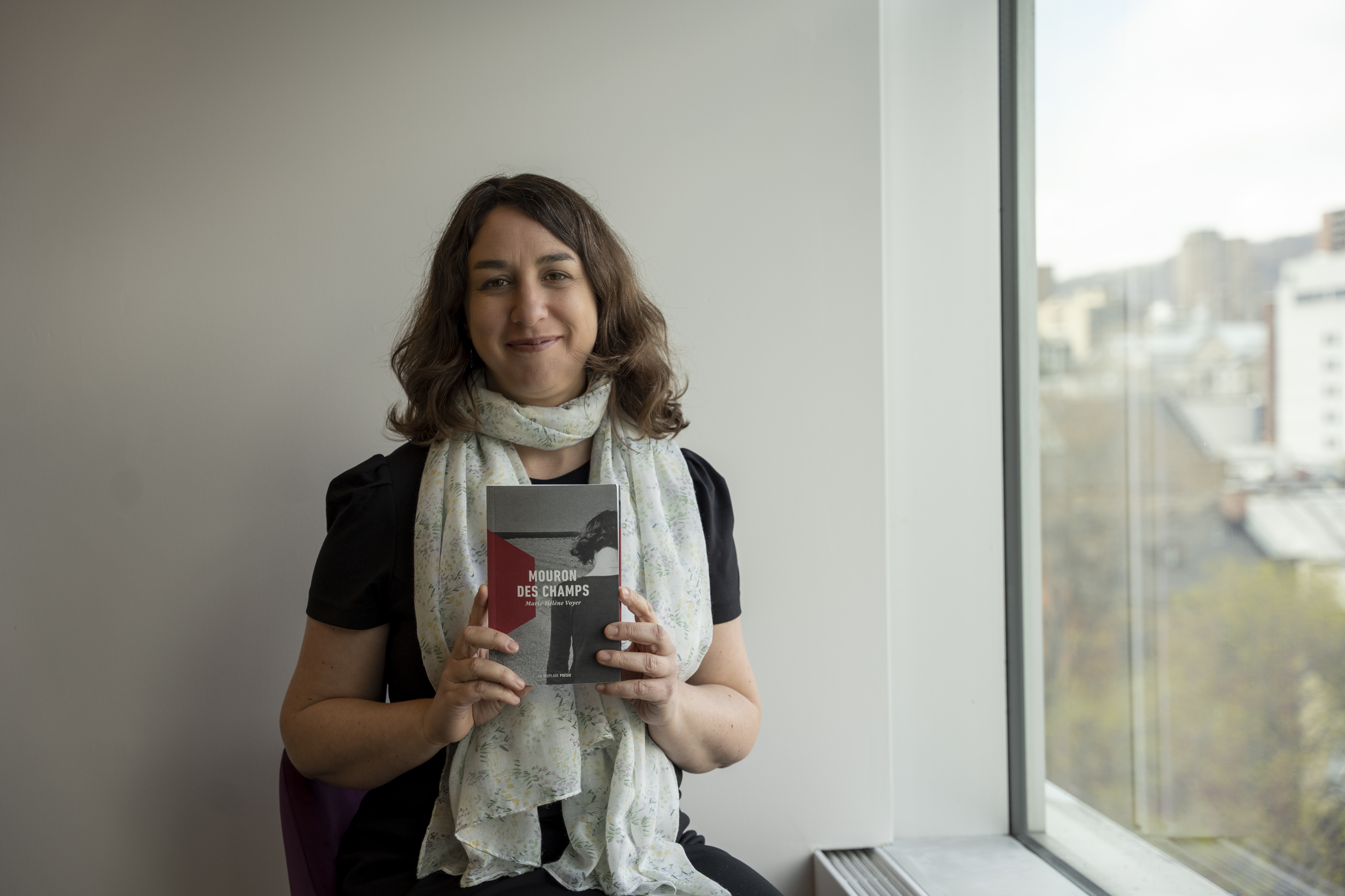 Esther Laforce, bibliothécaire de la Grande Bibliothèque et membre du balado « Signets au féminin », tenant le recueil  « Mouron des champs » de Marie-Hélène Voyer