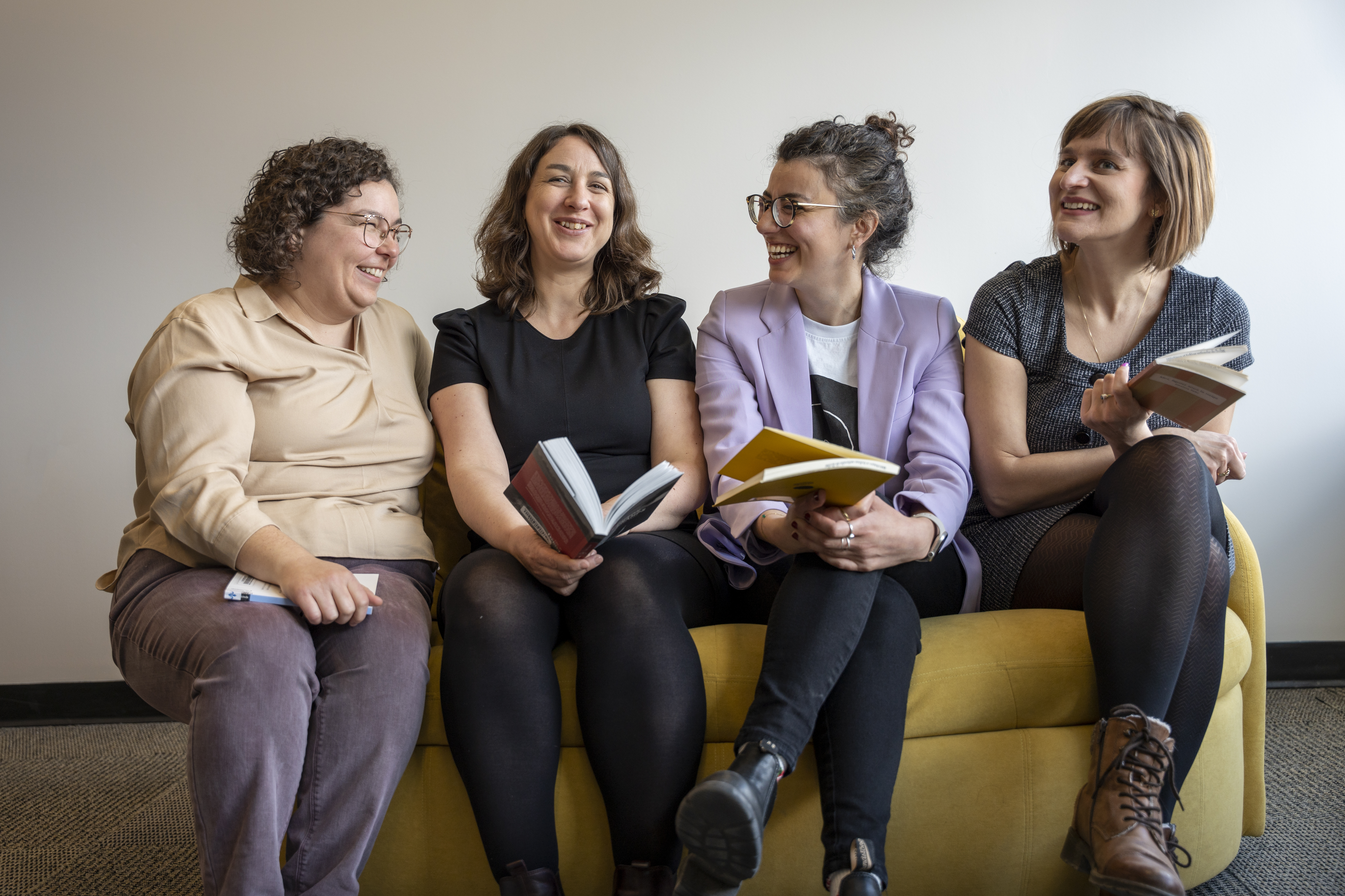 Les 4 bibliothécaires du balado "Signets au féminin" avec les recueils de poésie abordés riant ensemble sur un divan jaune