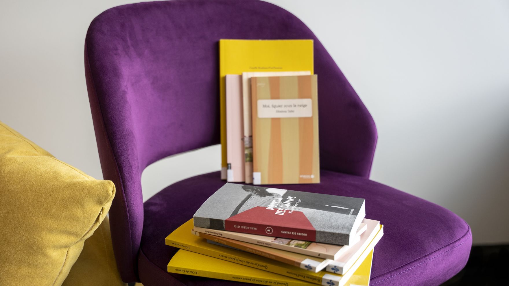 Plusieurs recueils de poésie québécoise sur un fauteuil violet