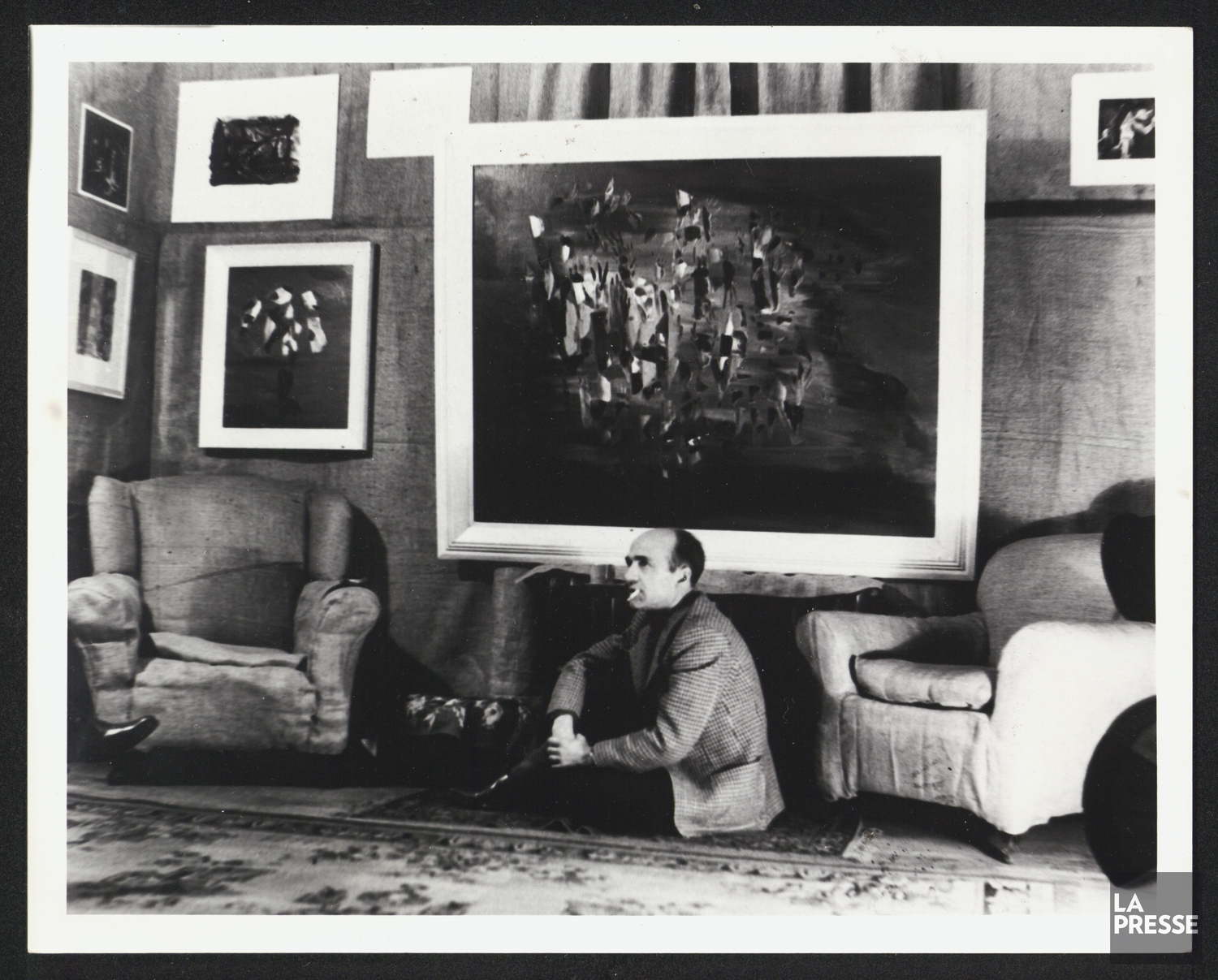 Paul-Émile Borduas, assis devant ses peintures