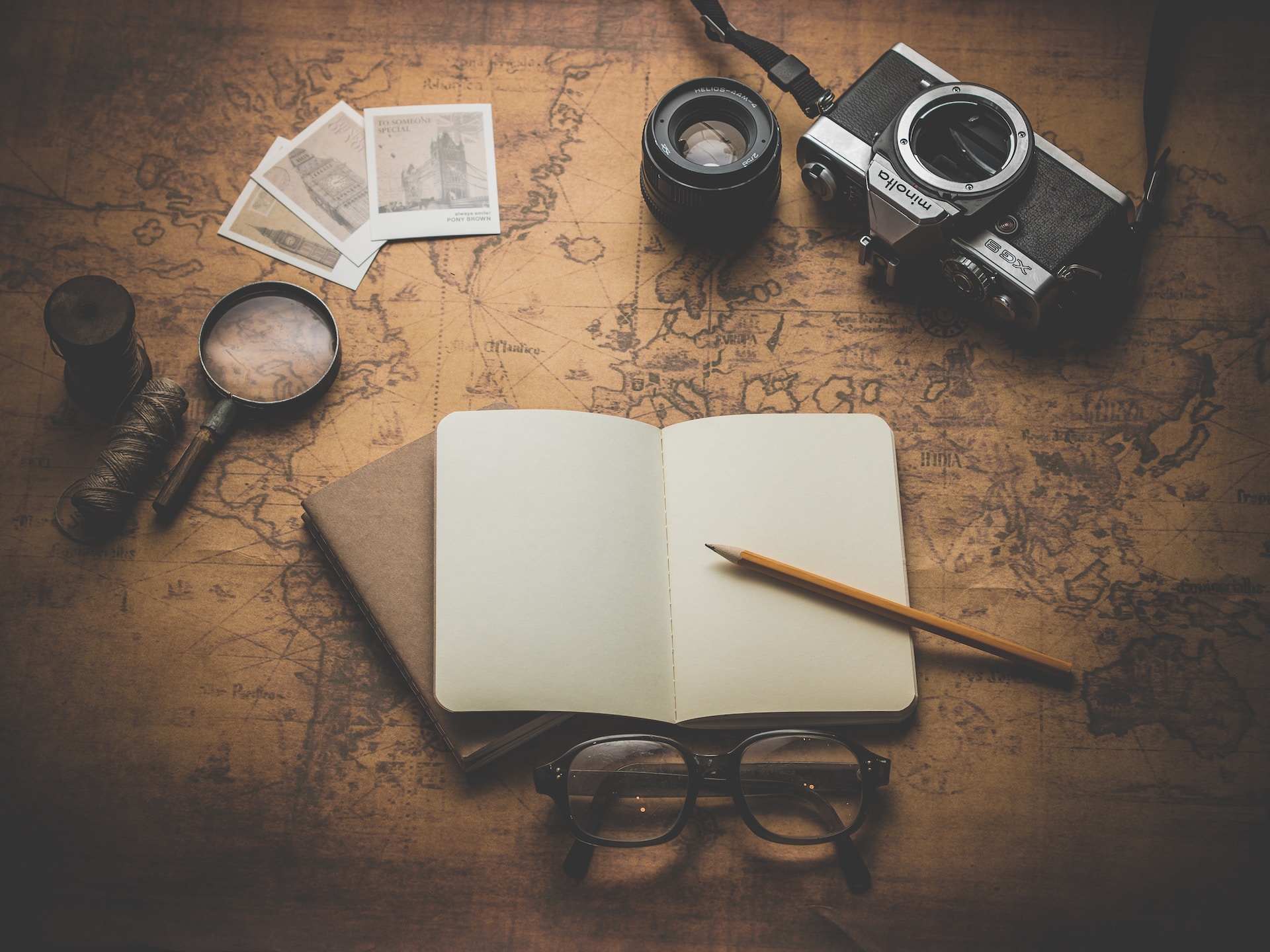 Objects sur une carte ancienne : loupe, appareil photo, carnet de notes, crayon, lunettes.