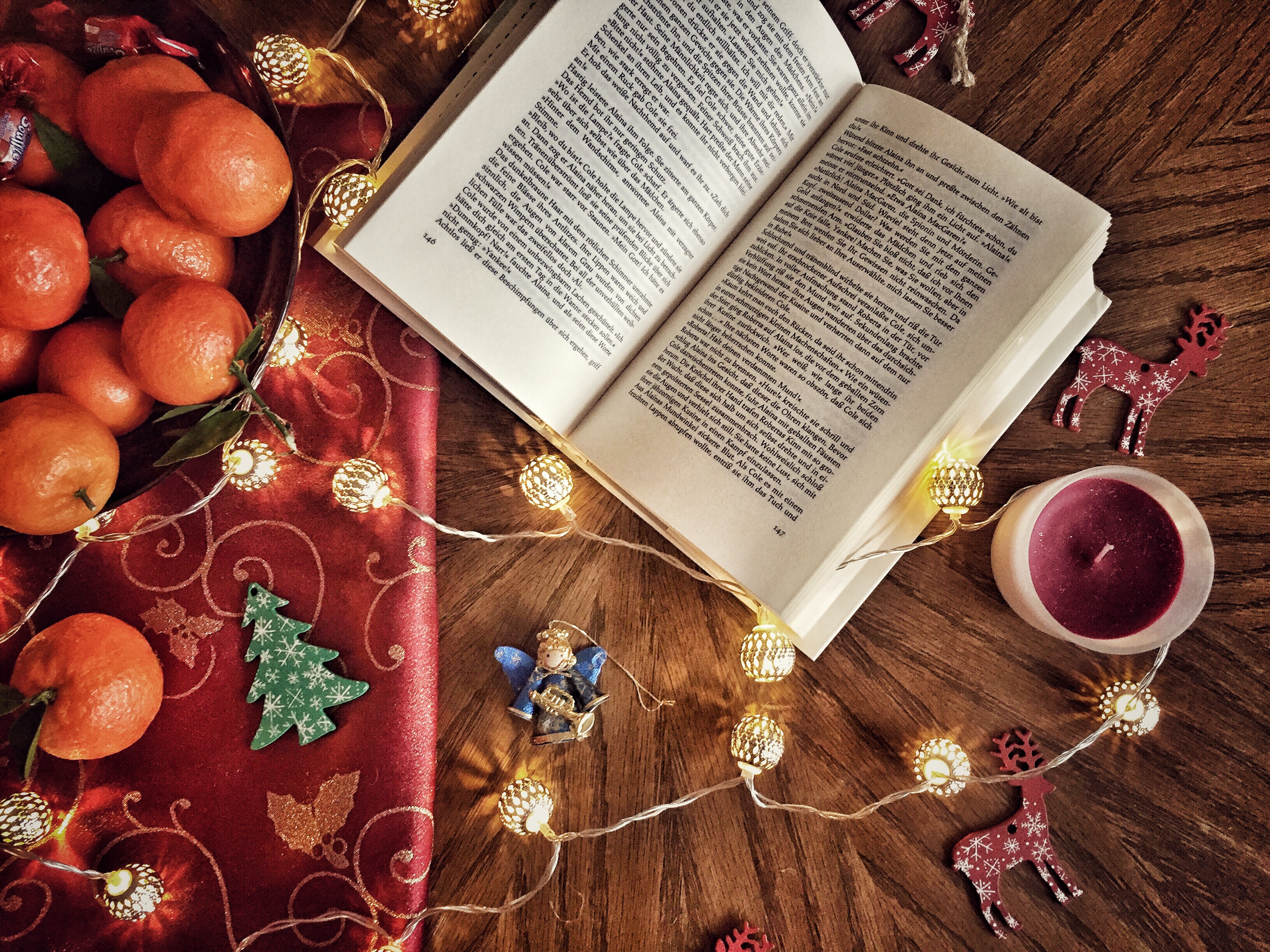 Livre ouvert entouré de guirlandes, de chandelles, d'oranges et de décorations de Noël