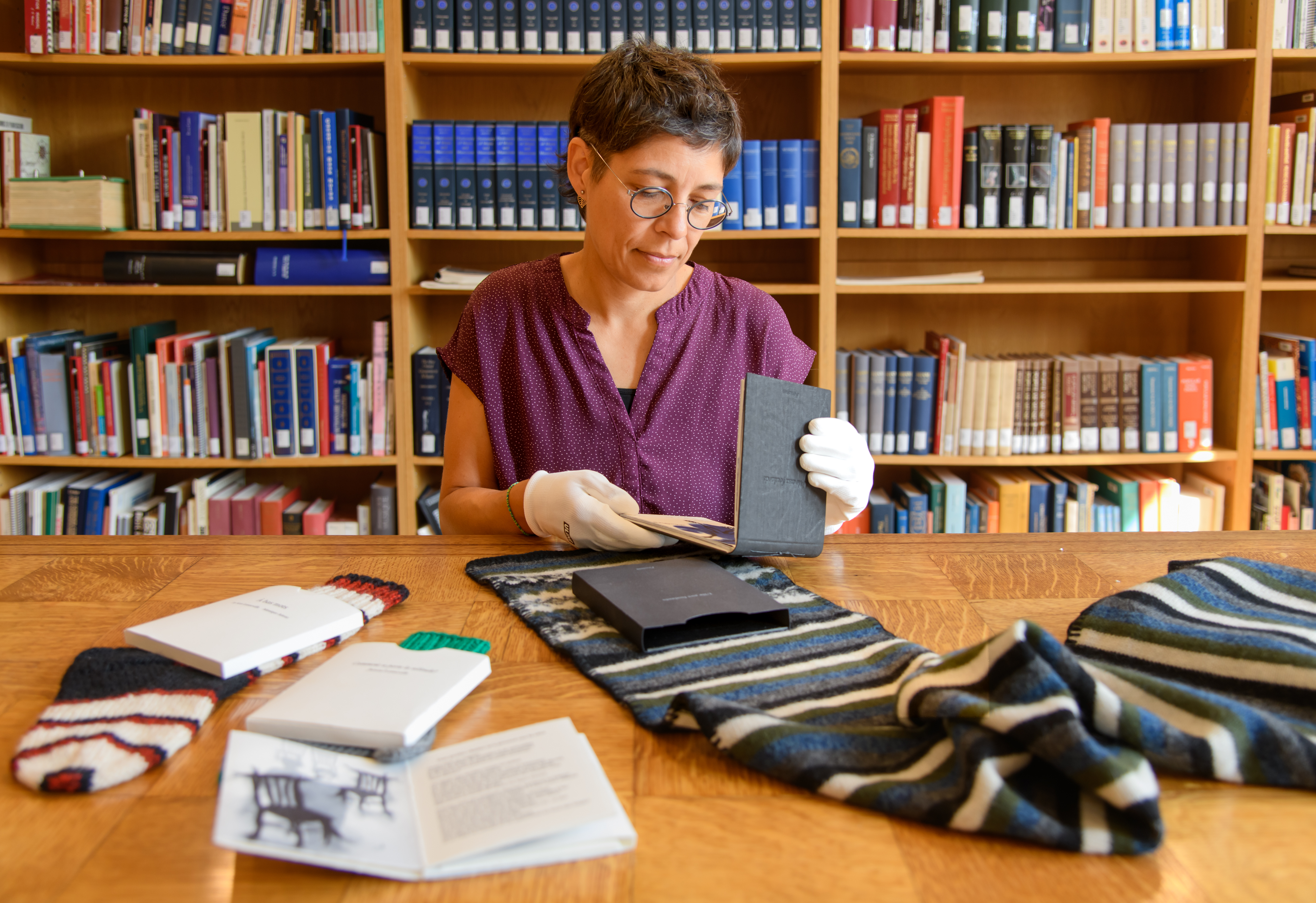 On aperçoit Isabelle manipulant des livres d'artistes. Ceux-ci ont la particularité d'être présentés tantôt dans un foulard, tantôt dans une chaussette.