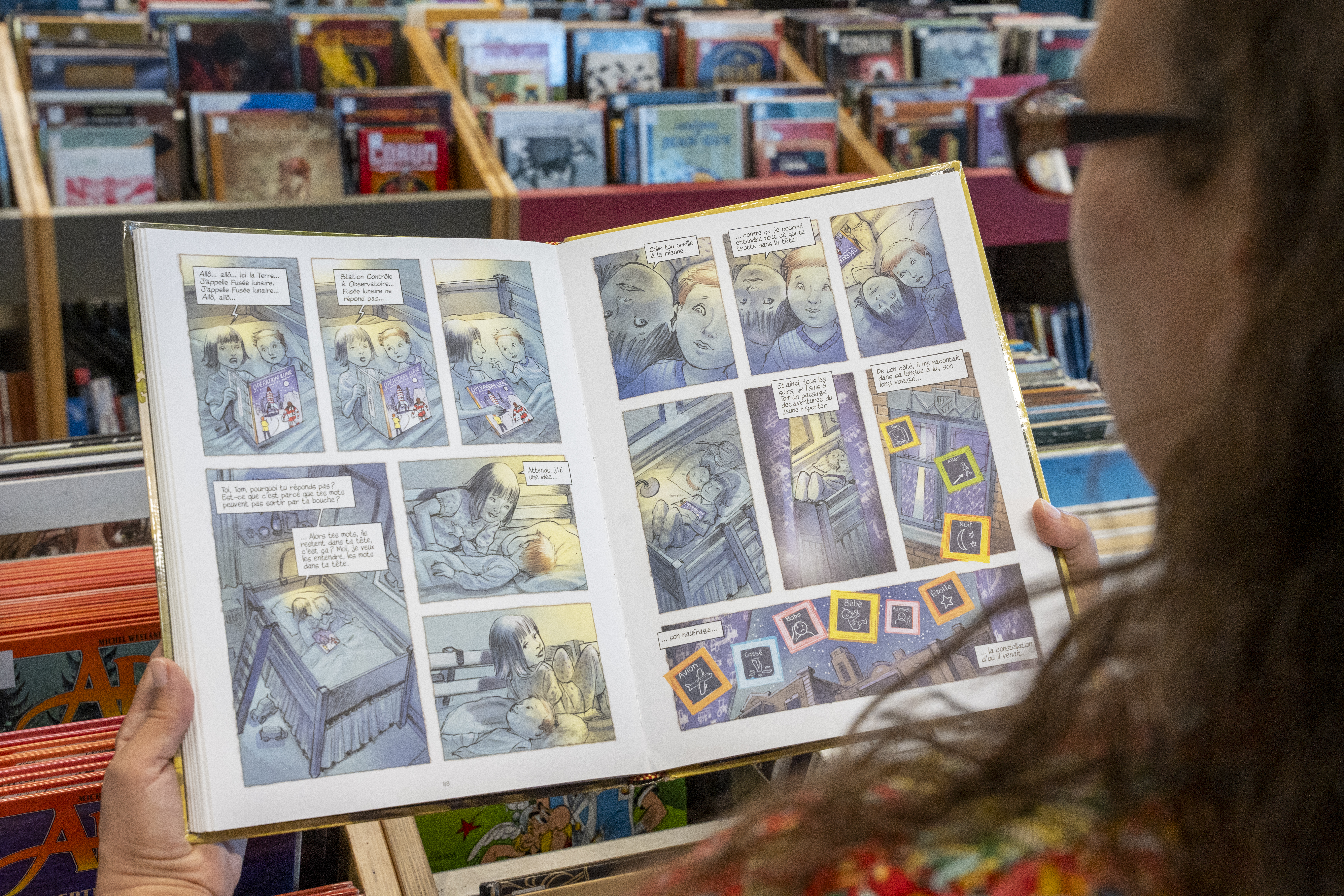 Sur une page du livre Le petit astronaute, de Jean-Paul Eid, deux enfants lisent ensemble un livre de Tintin.