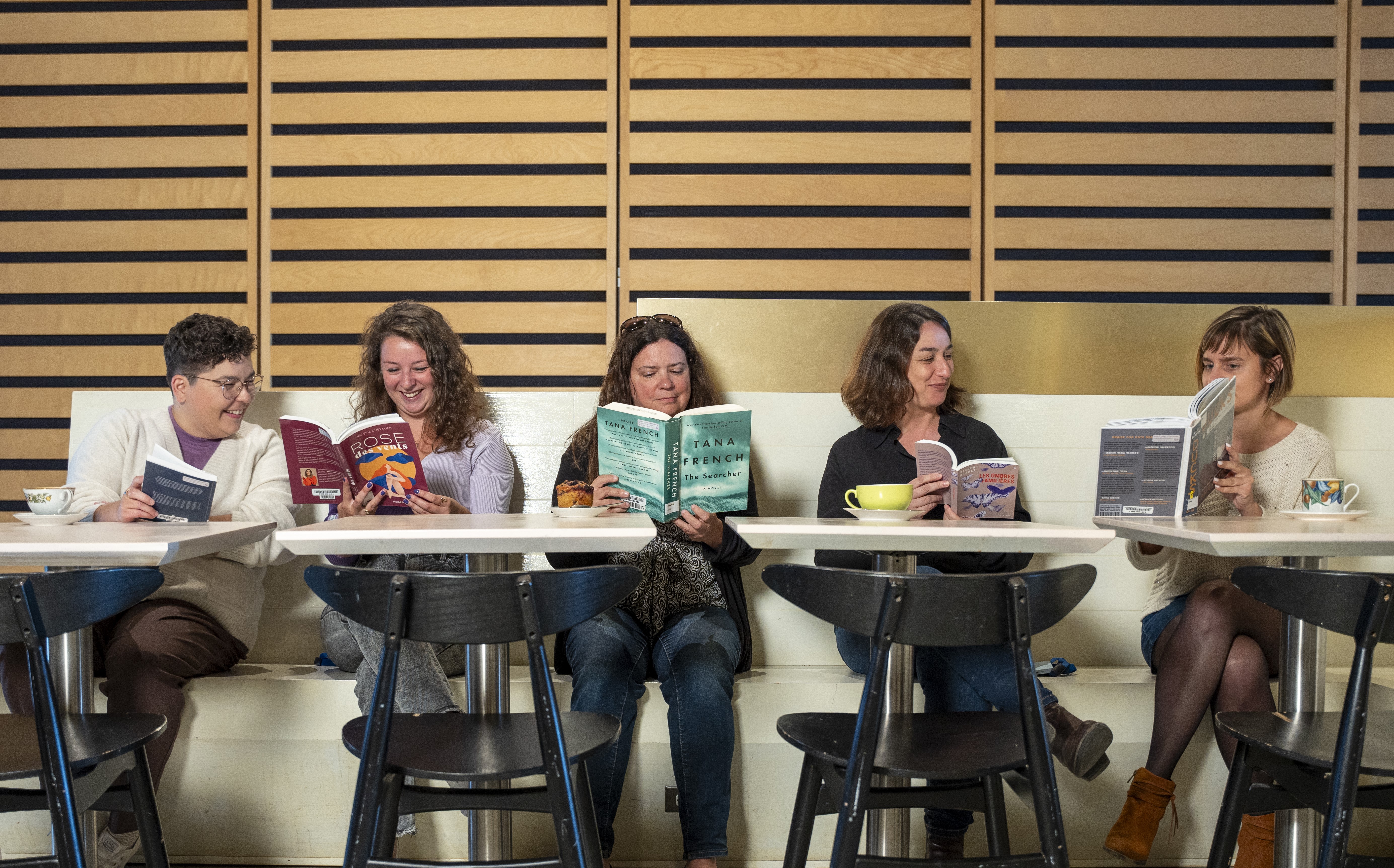 Cinq femmes lisent des livres côte-à-côte.