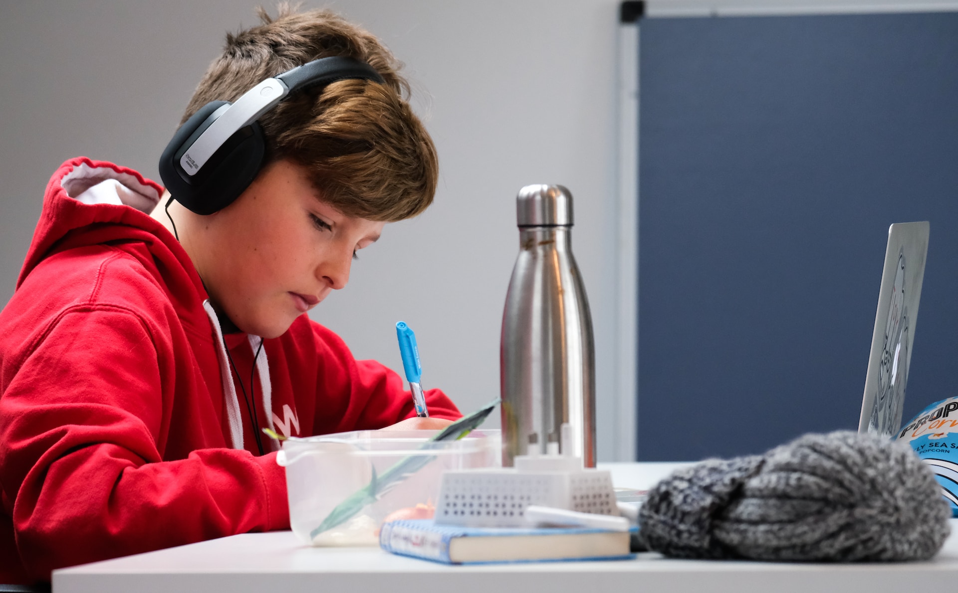 Un garçon fait ses devoir avec un casque d'écoute.