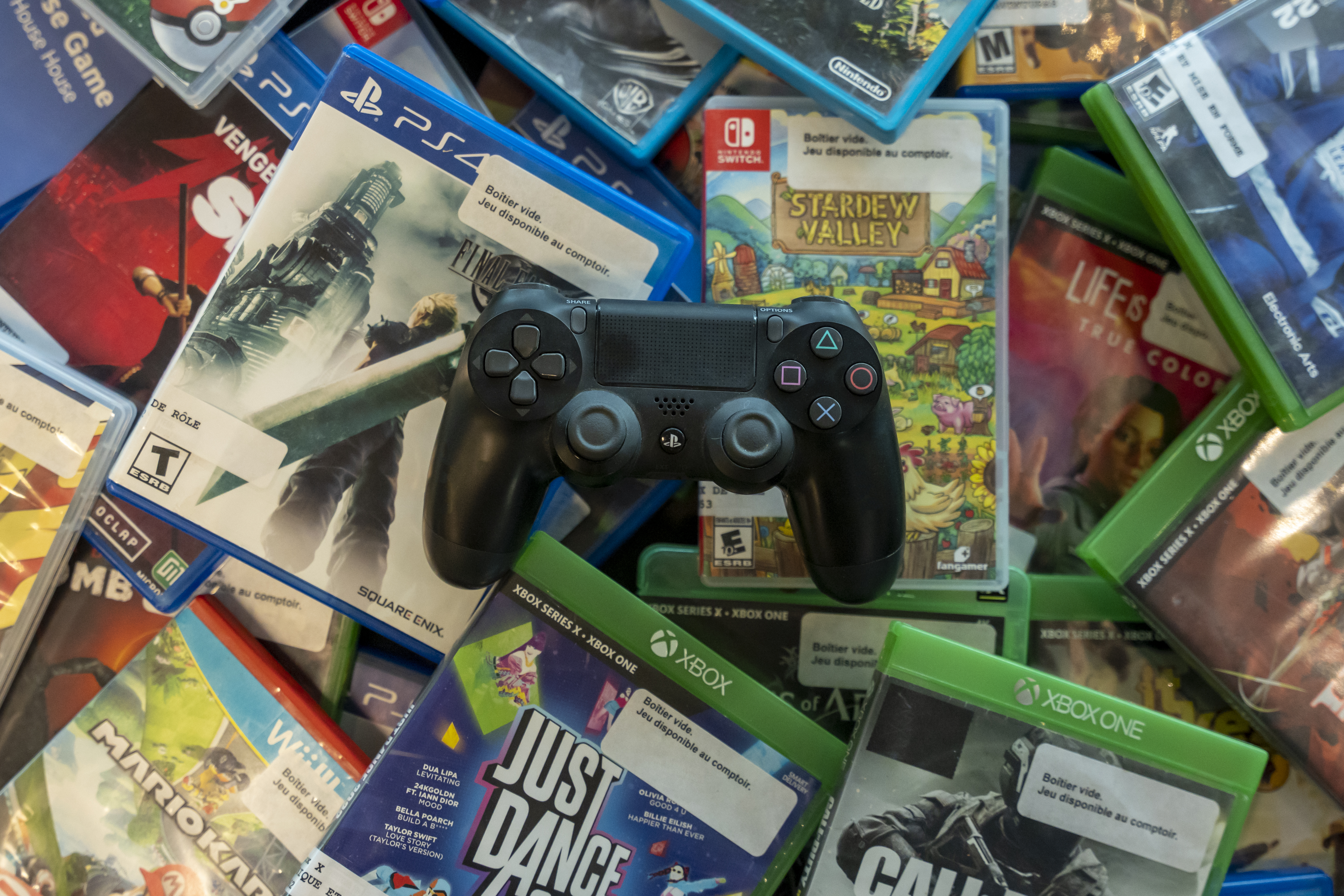 Manette de PS4 sur une pile de boitiers de jeux vidéo