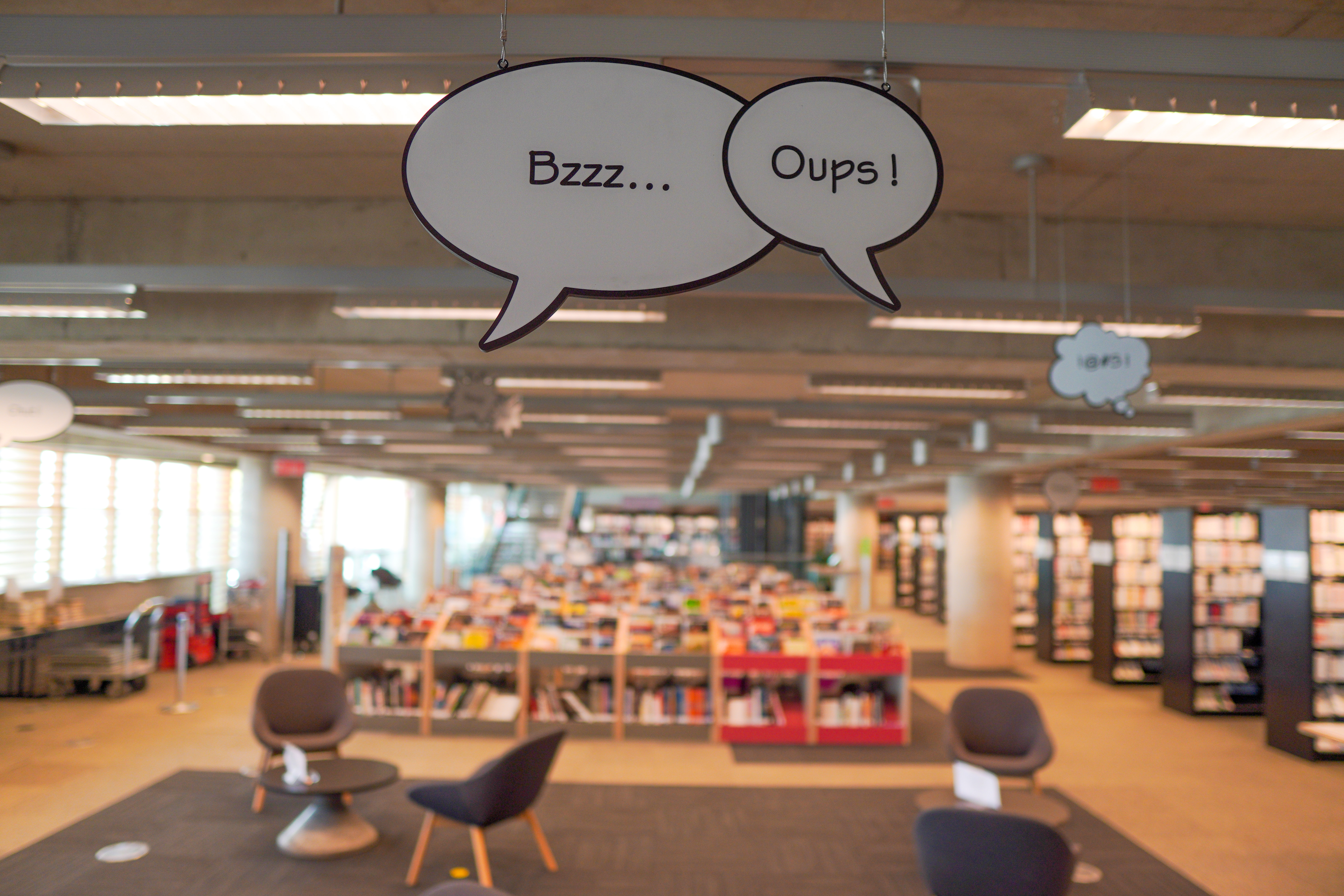 Phylactères contenant les onomatopées Bzzz et Oups suspendus au plafond de l'espace BD de la Grande Bibliothèque