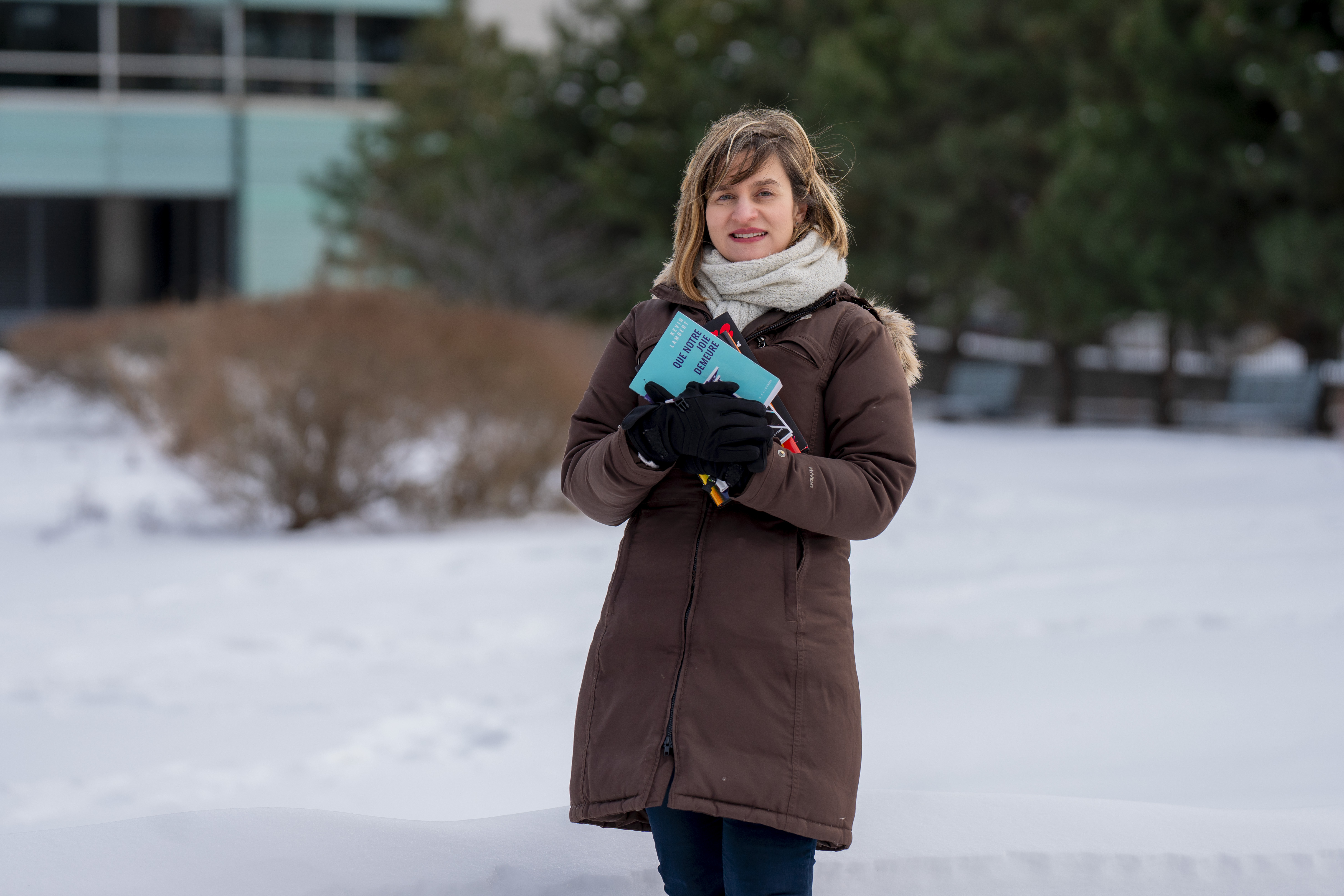 Une femme tient des livres, dans la neige.