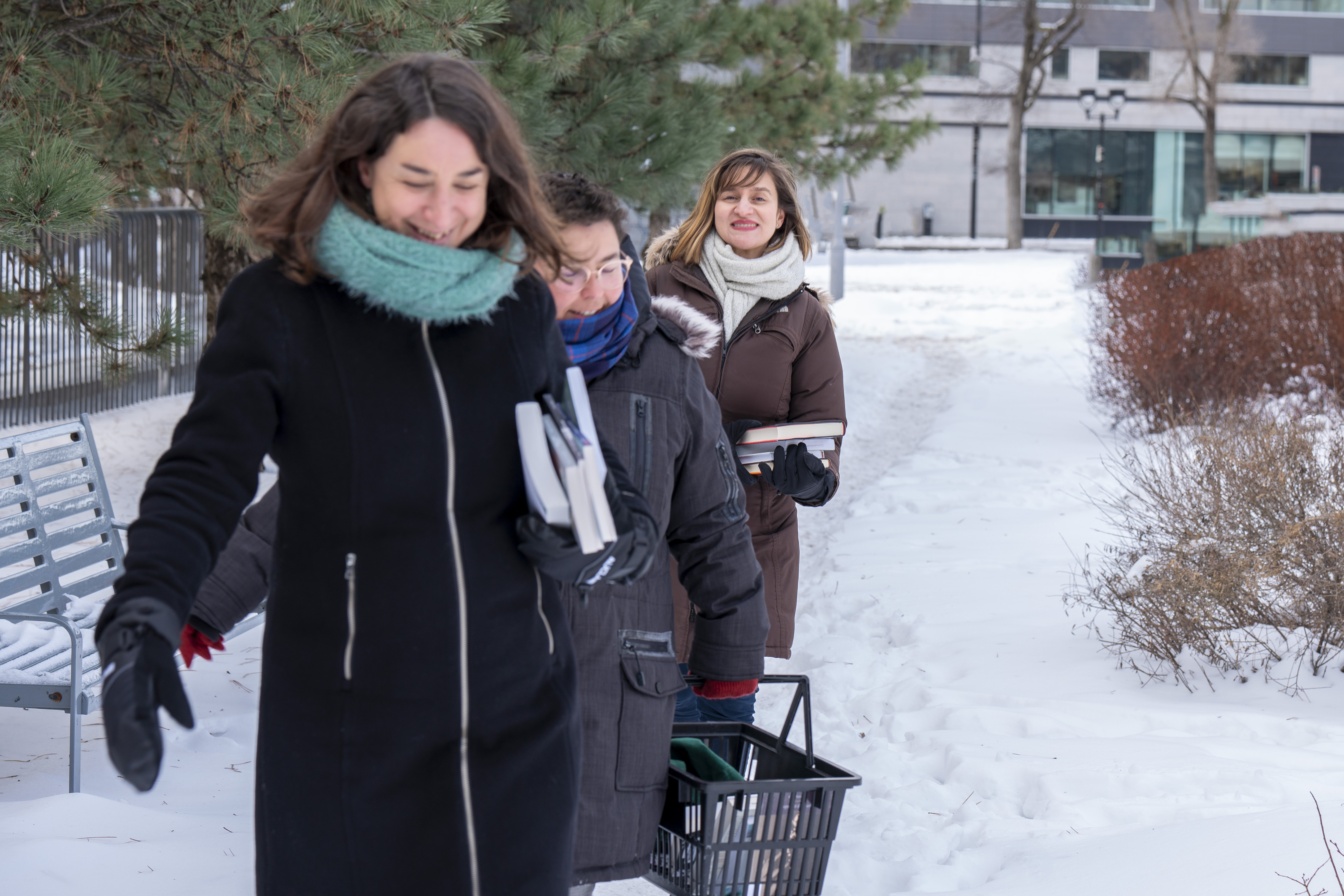 Trois femmes marchent dans la neige en tenant des livres.