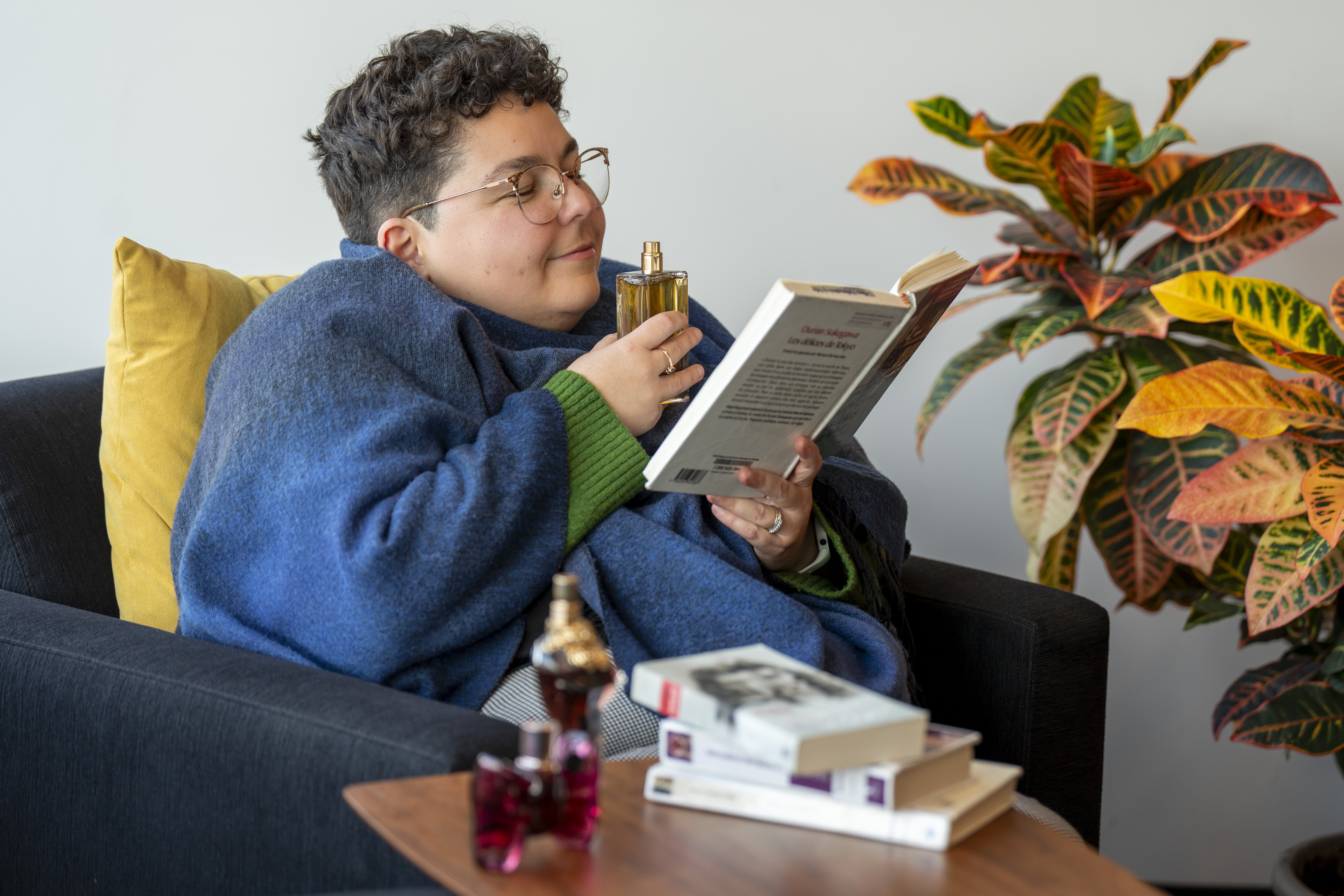 Une femme lit un livre en sentant un parfum.