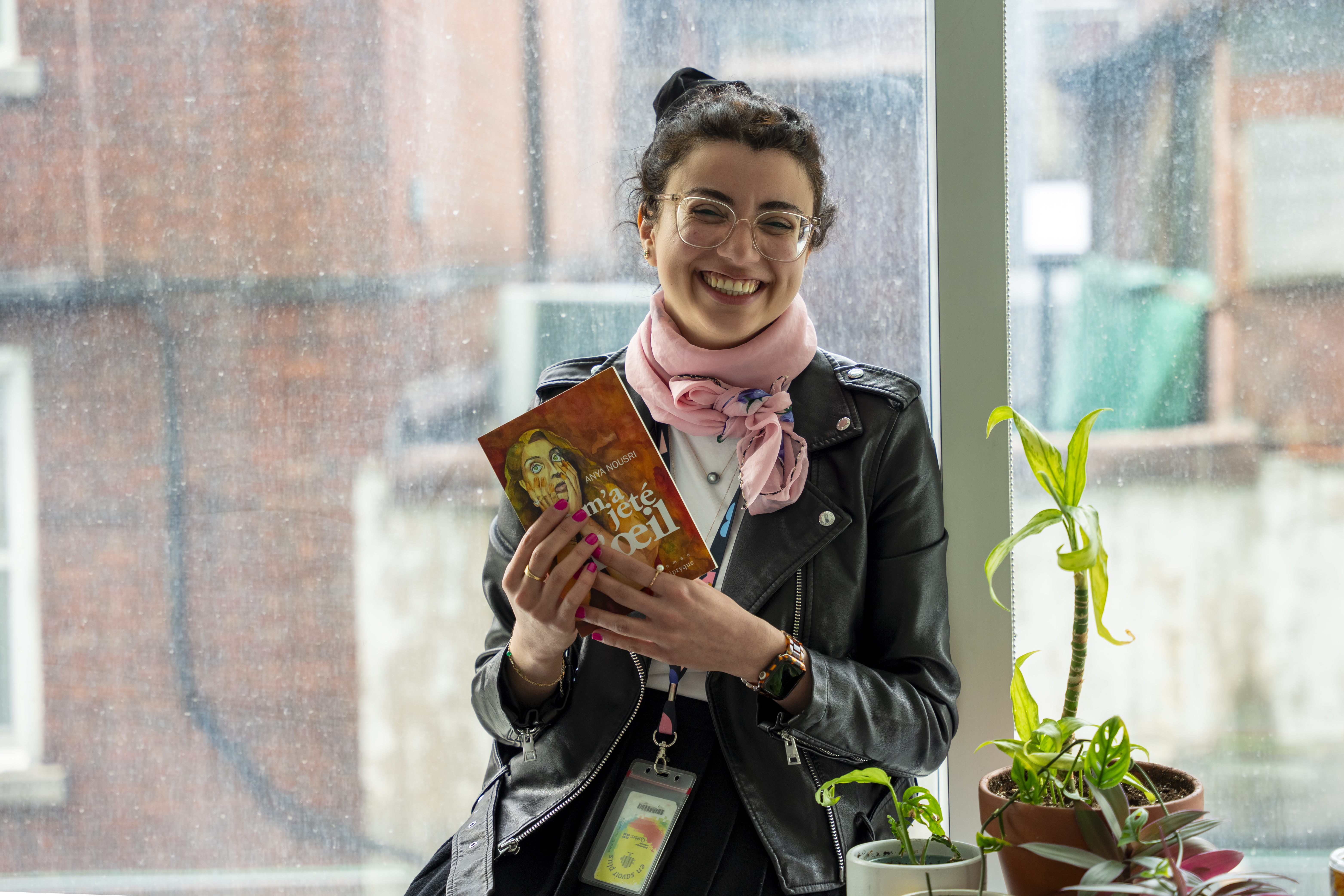 Femme près d'une fenêtre montrant un livre.