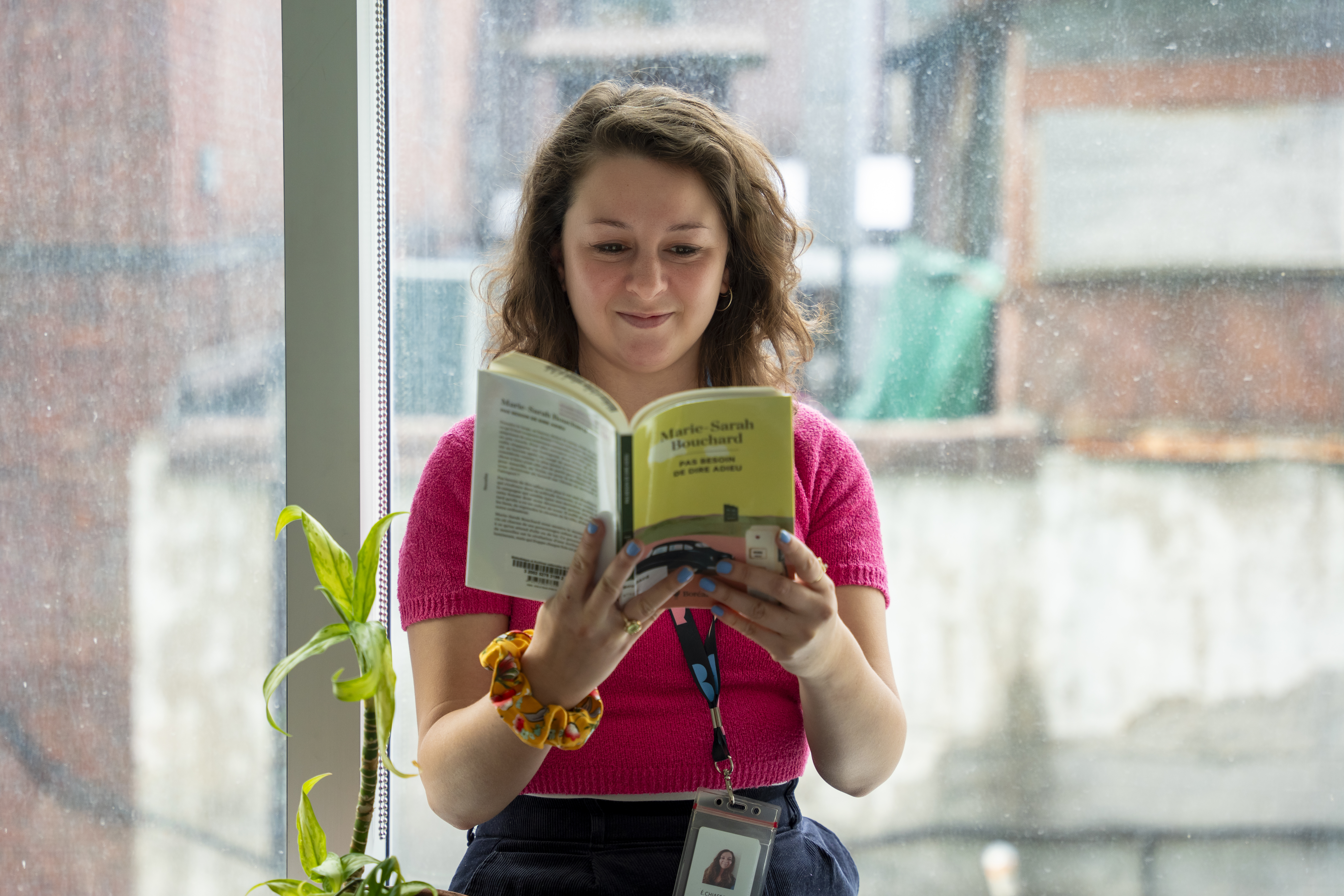 Femme lisant un livre près d'une fenêtre.