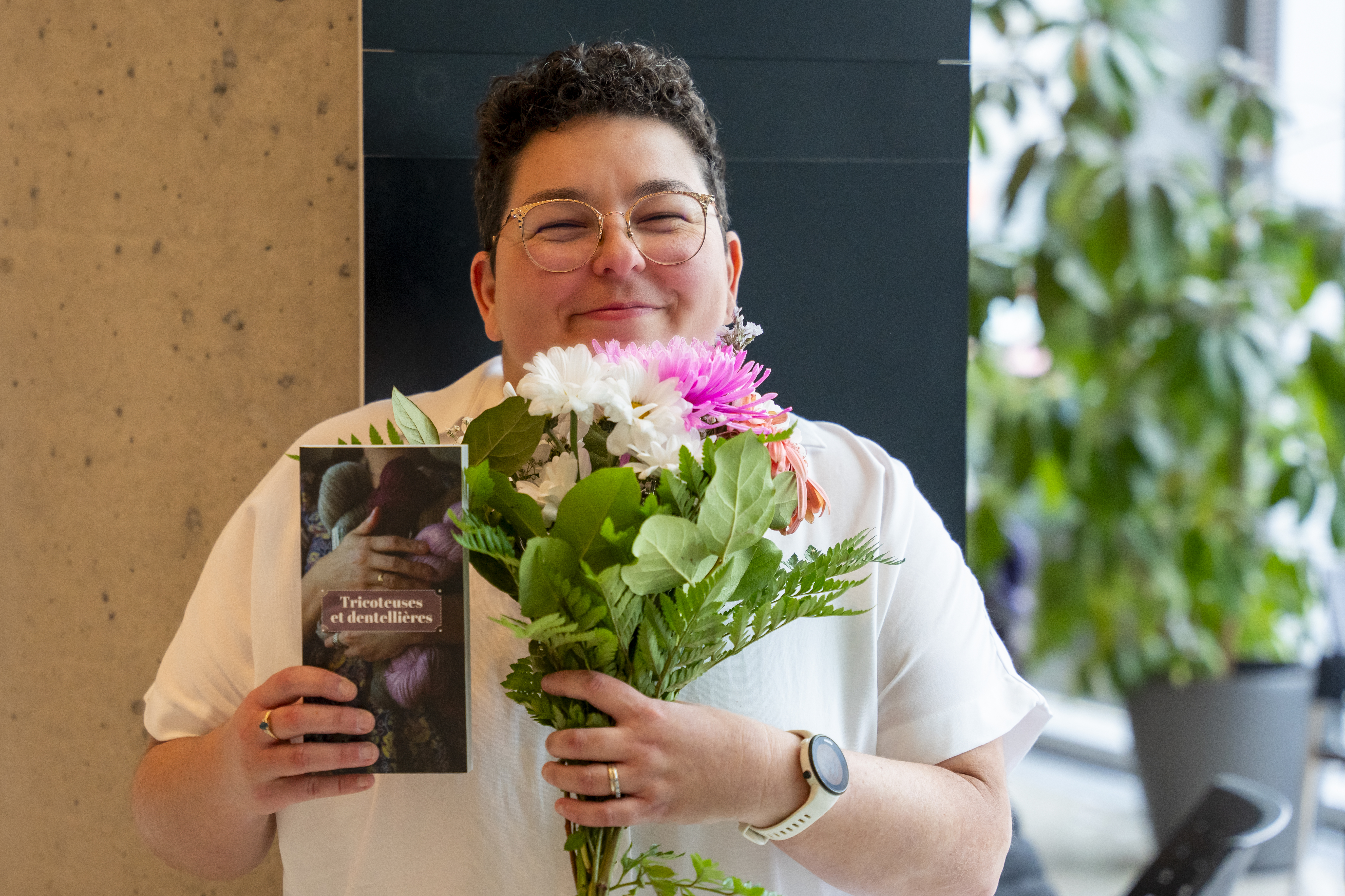 Femme tenant un livre et un bouquet de fleurs.