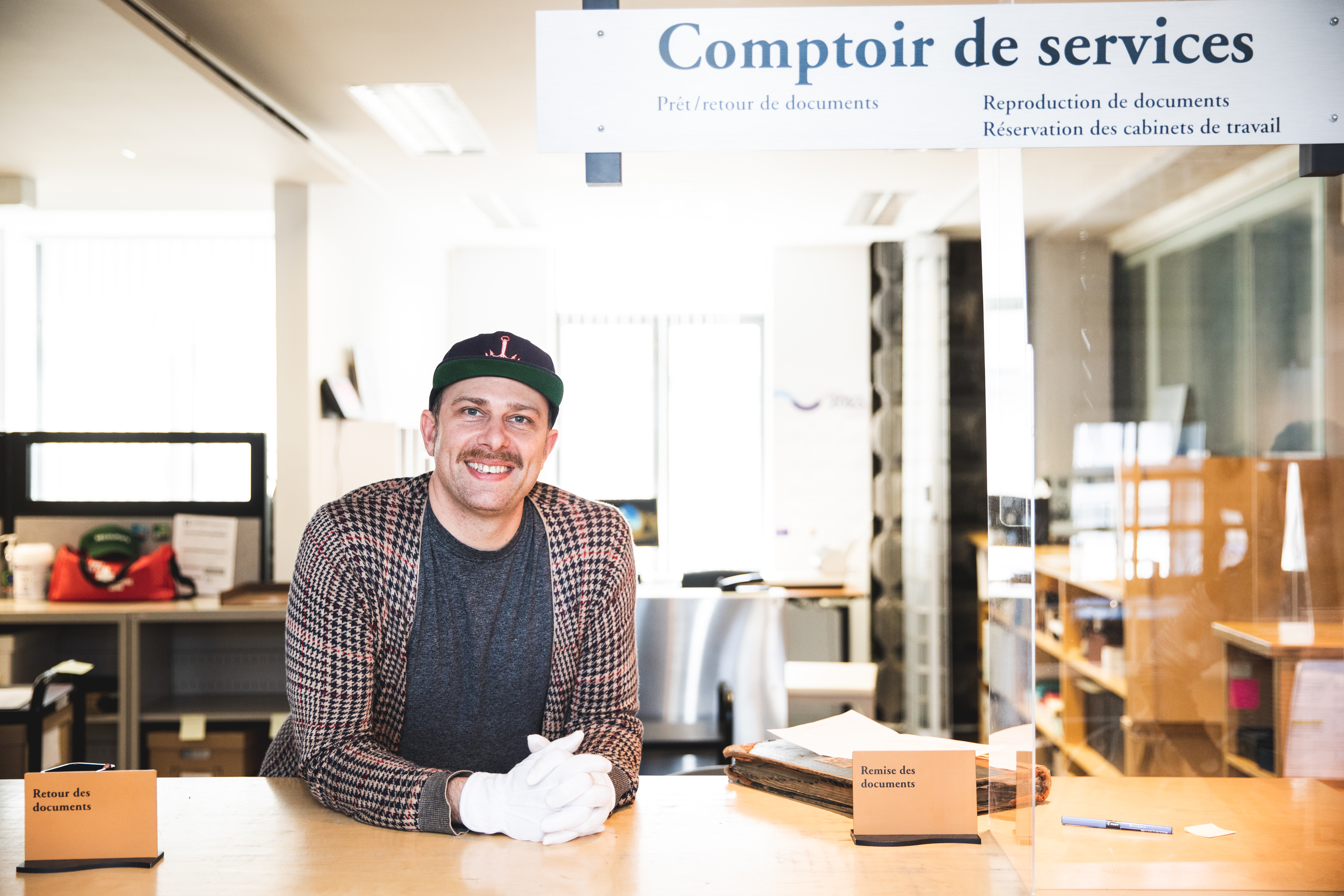 Un archiviste souriant se tient derrière un comptoir de services.