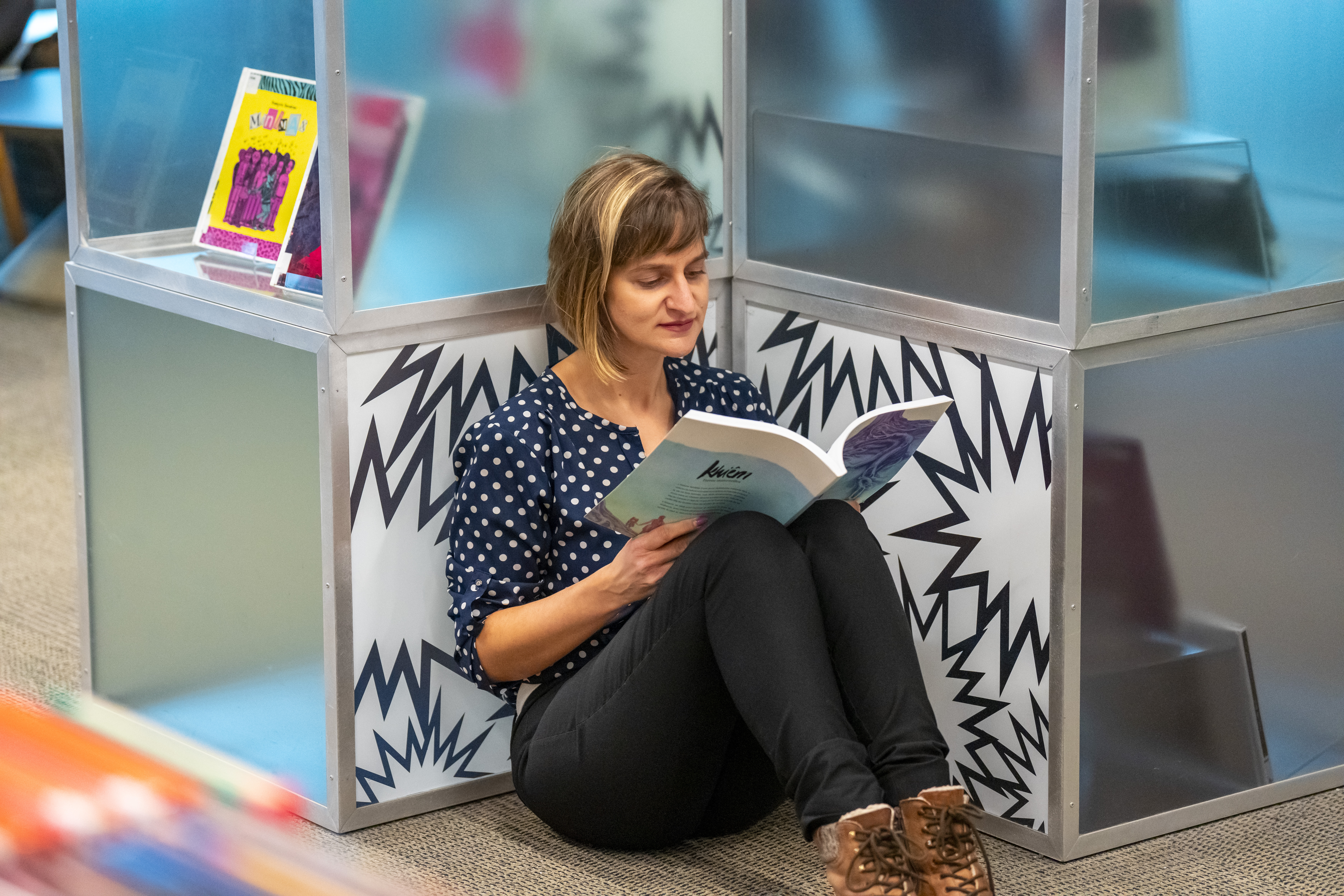 Femmes assise par terre lisant un bande dessinée.