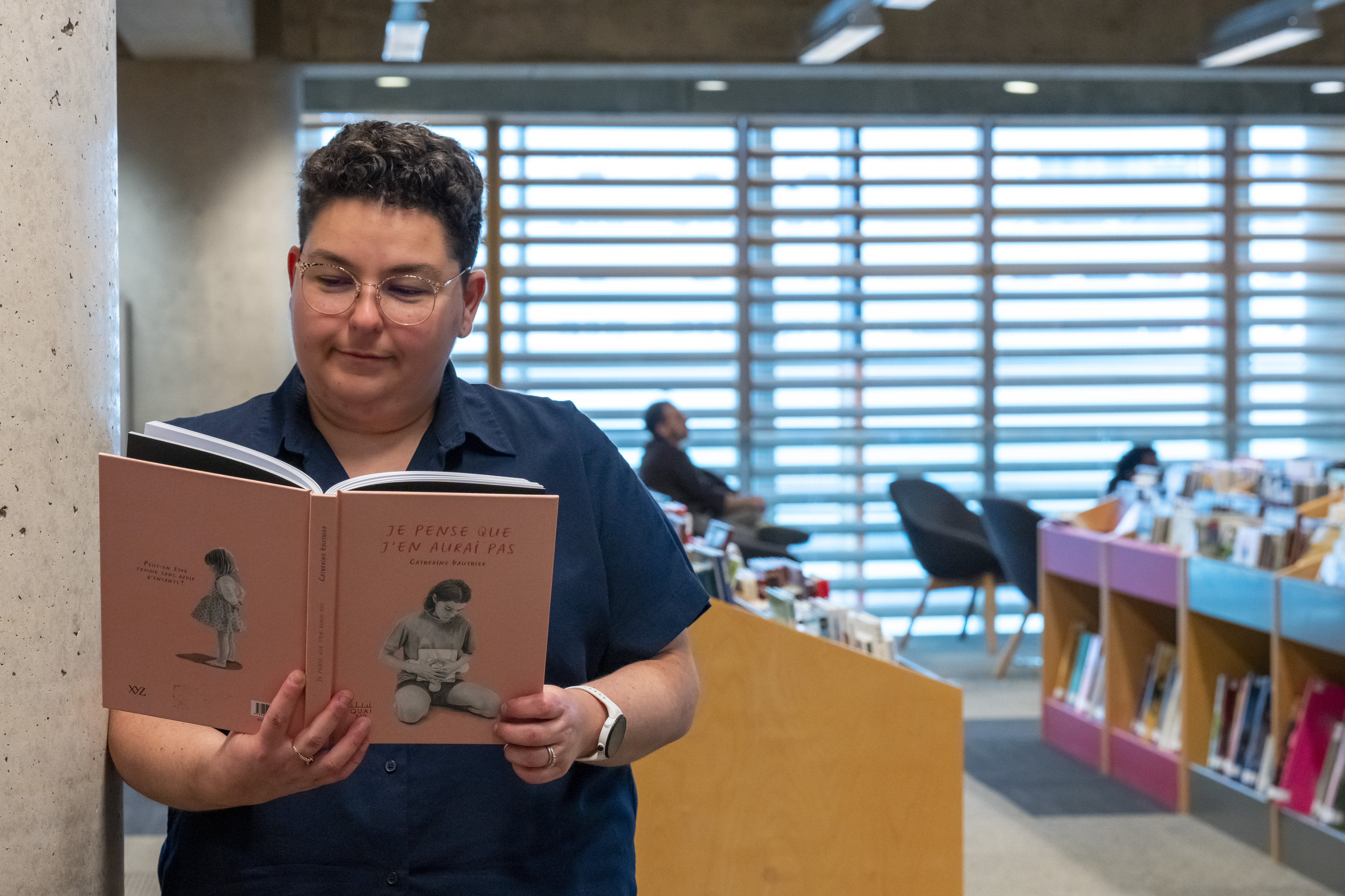 Une femme lit la bande dessinée « Je pense que j'en aurai pas » de Catherine Gauthier.