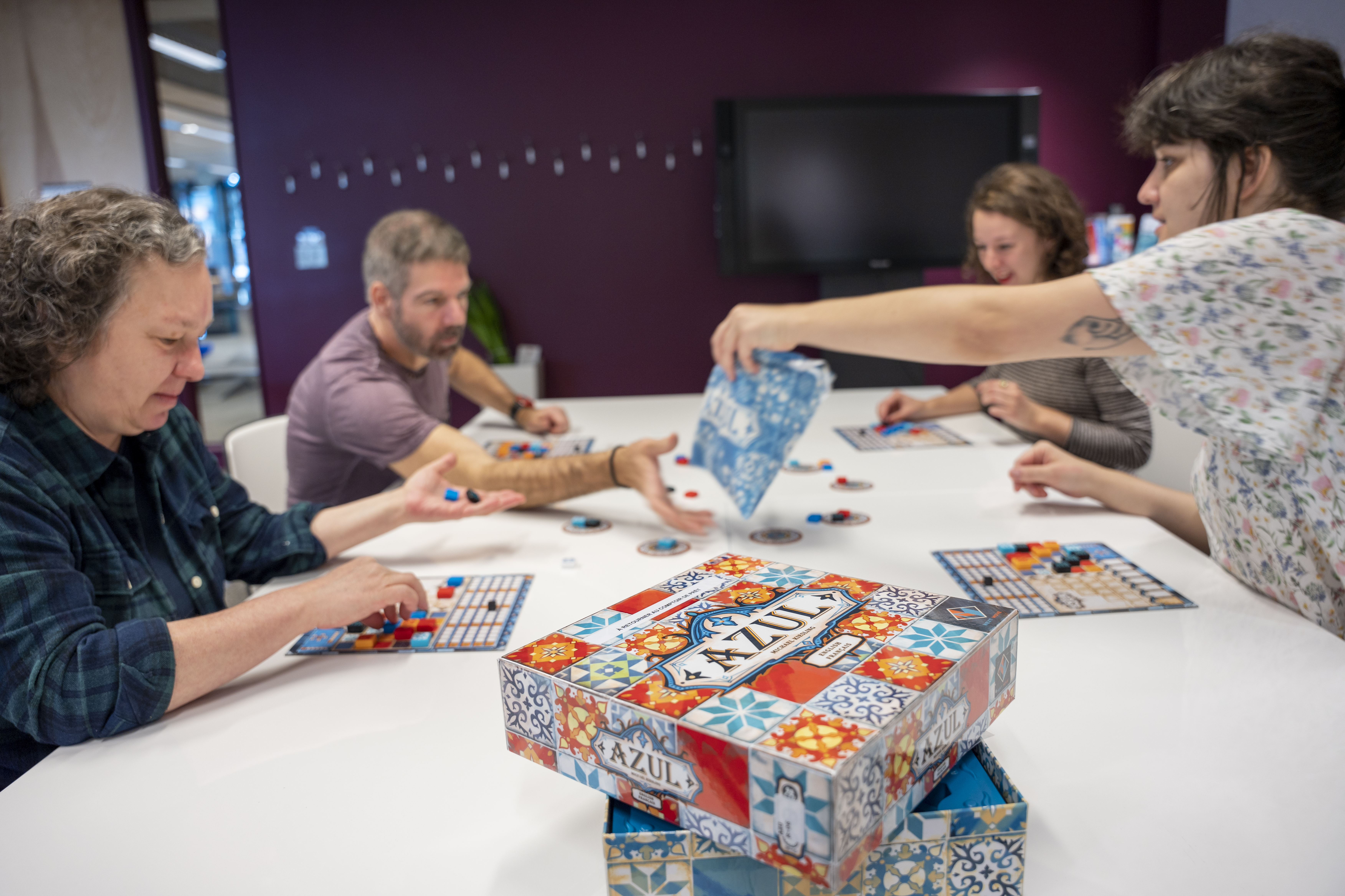 4 personnes autour d'une table jouant à un jeu de société