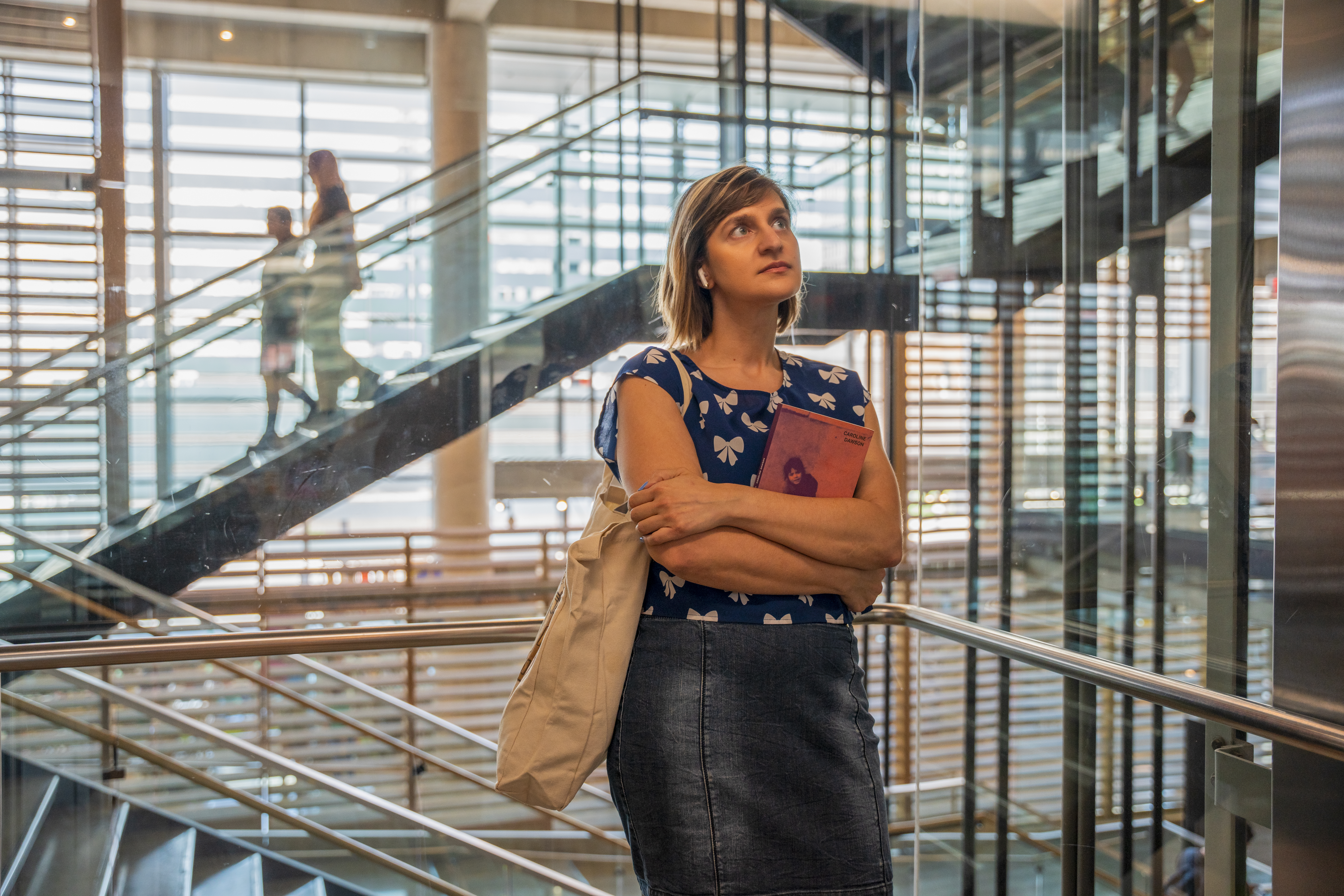 À la Grande Bibliothèque, une femme portant des écouteurs tient le livre Là où je me terre de Caroline Dawson.