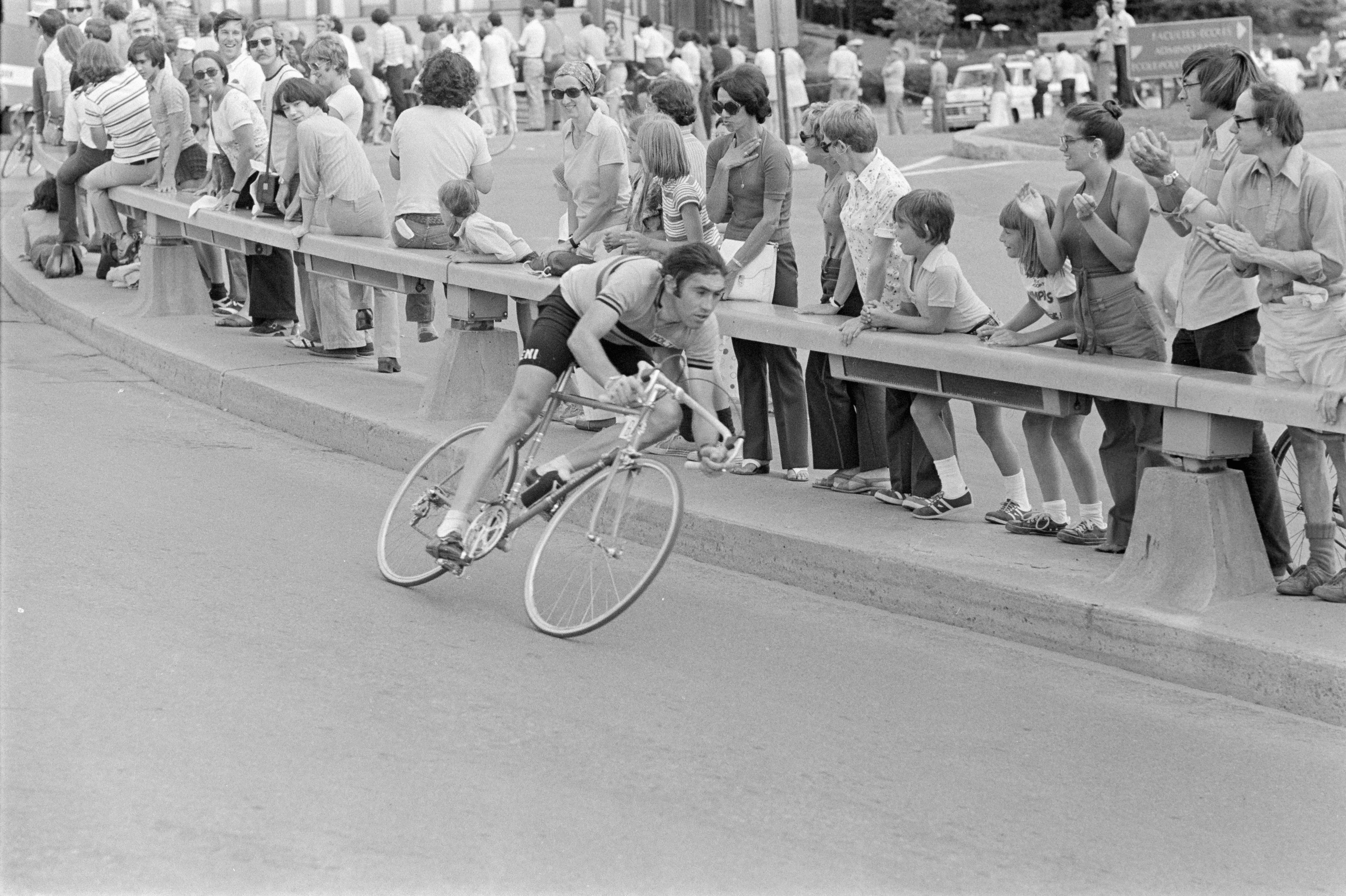 Coureur cycliste négociant un virage, devant une foule de spectateurs.