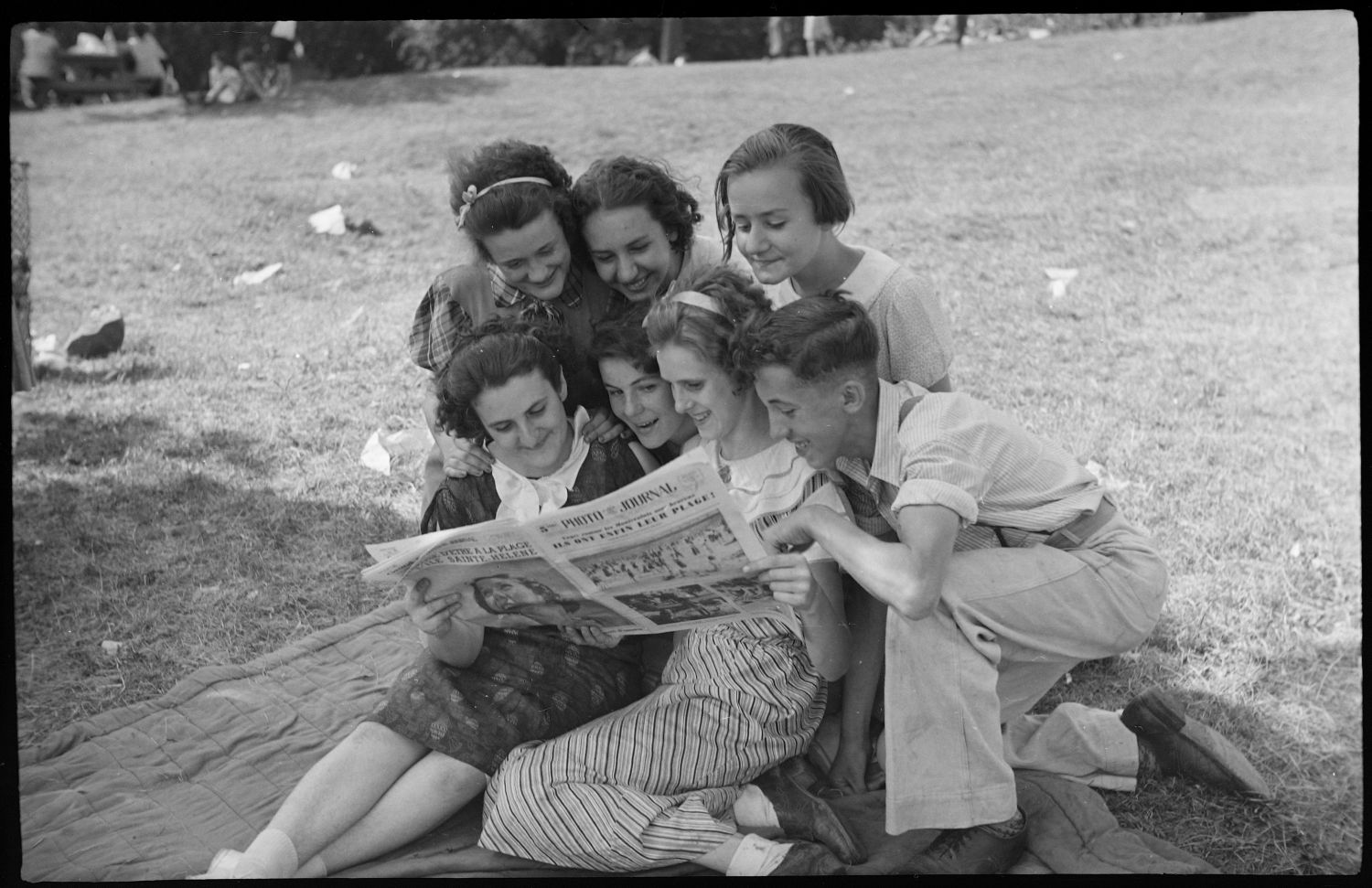 Groupe de jeunes des années 1930 rassemblé pour lire un journal
