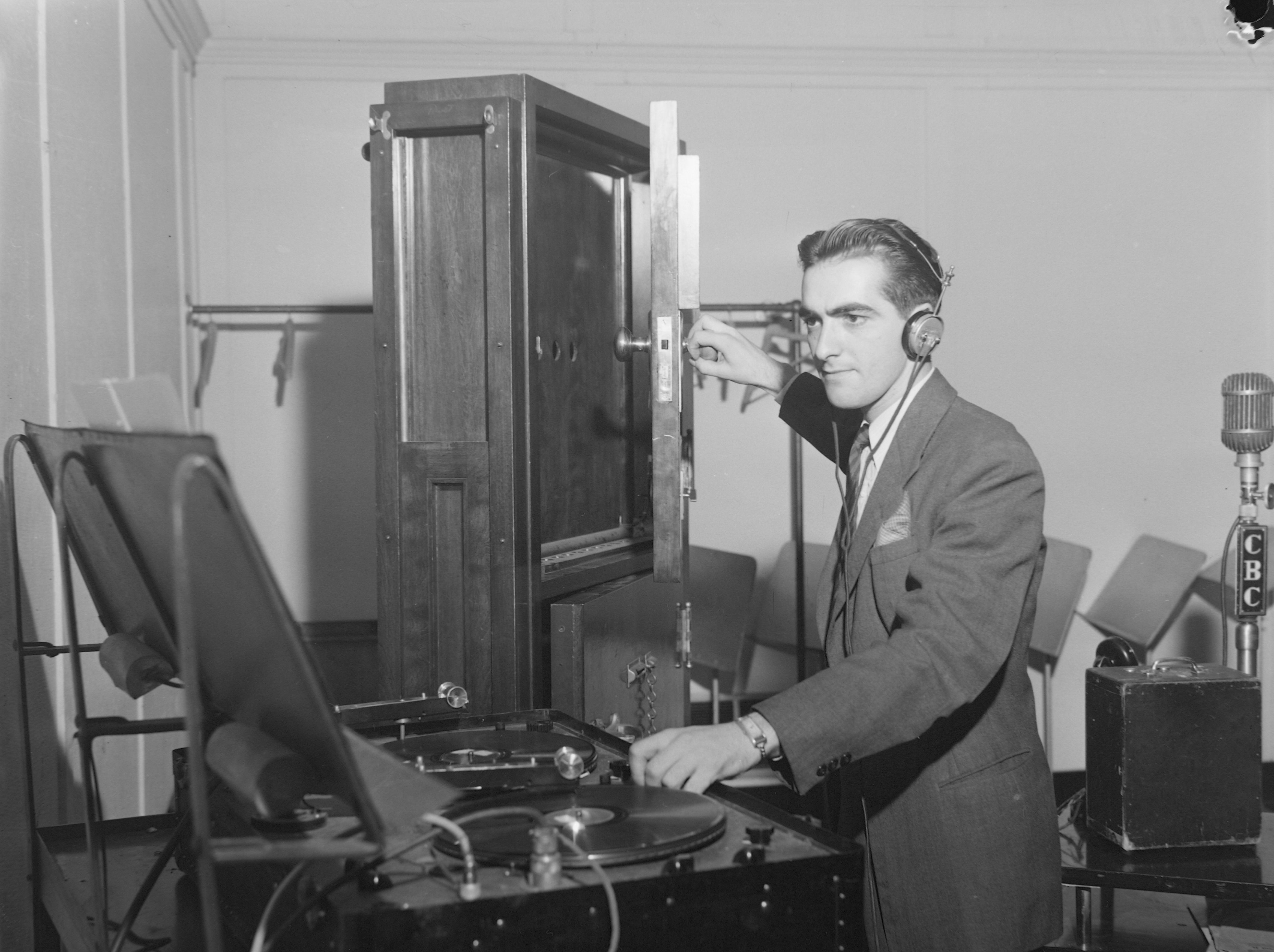 Une personne portant des écouteurs manipule de l’équipement audio et la porte d’une armoire, afin d’émettre un bruit.
