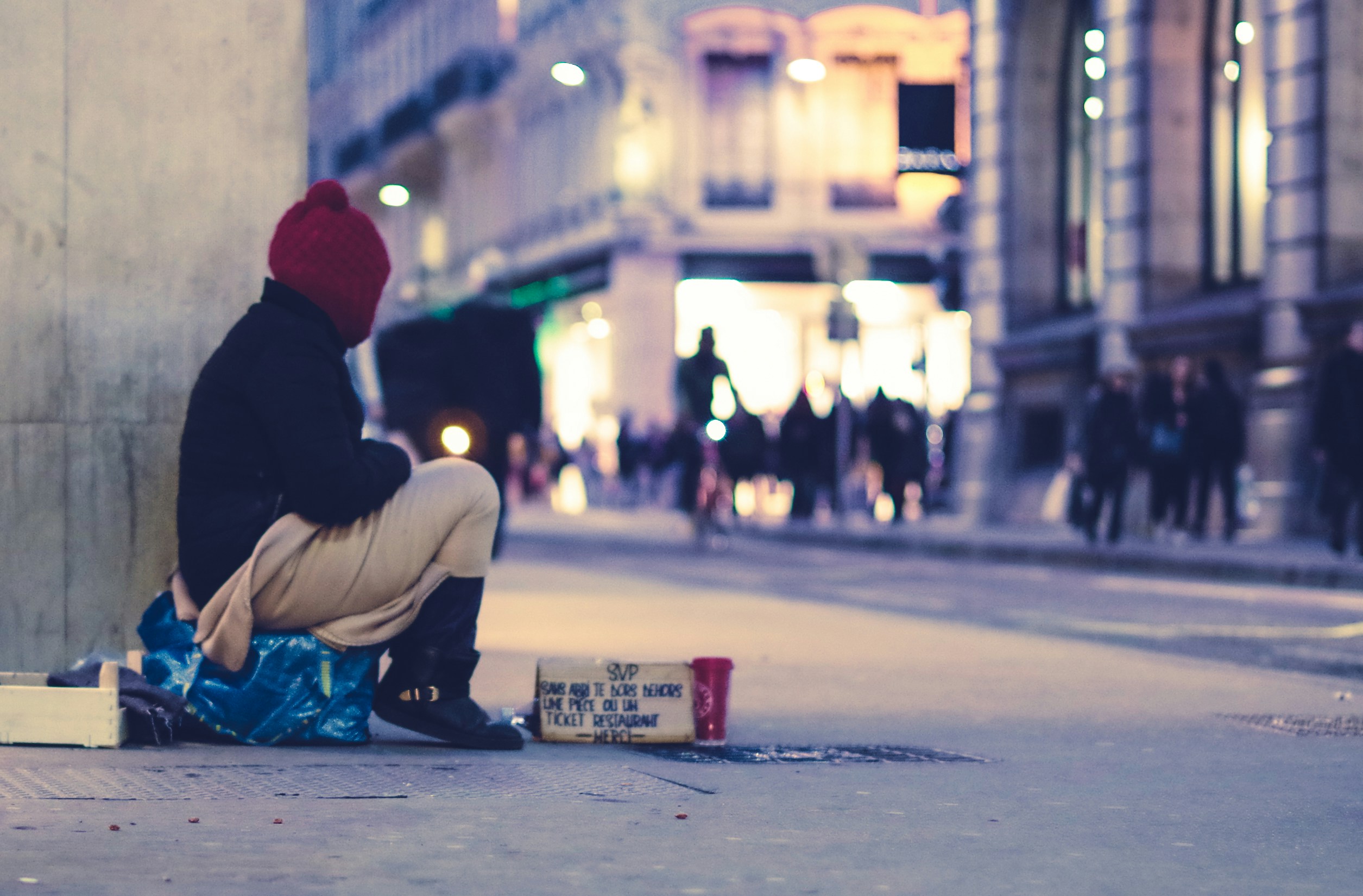 Personne sans-abri assis sur un trottoir.