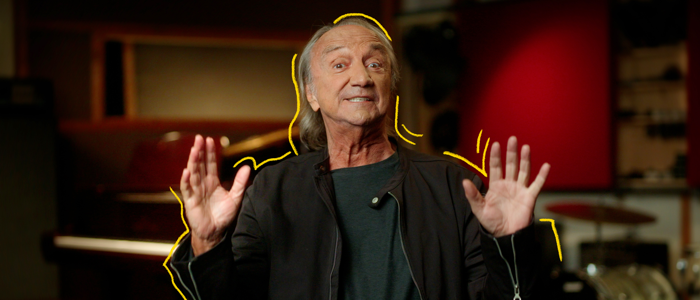 Le chanteur Claude Dubois levant les mains dans un studio de musique