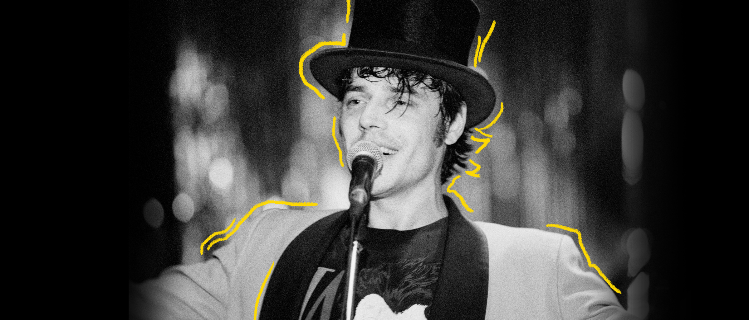 Photo d'archives en noir et blanc de Jean Leloup, jeune, chantant avec un chapeau haut de forme noir