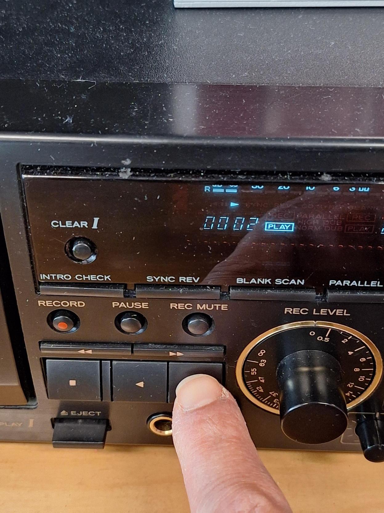 Appareil de lecture de cassette audio. Un doigt appuie sur le bouton Play.