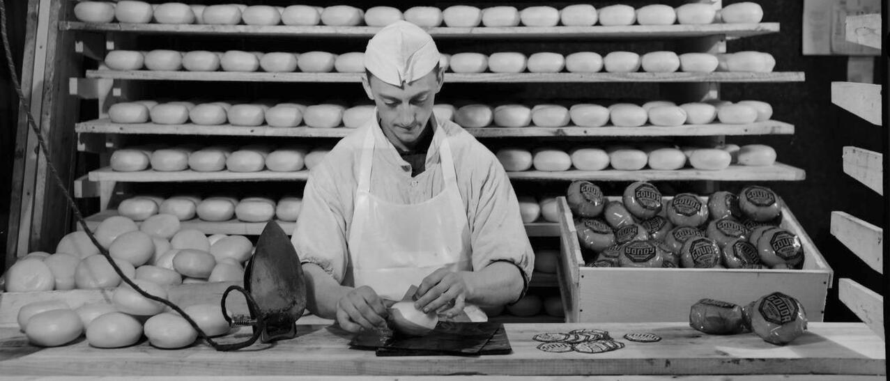 Homme emballant un fromage.