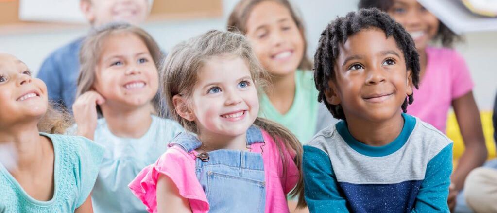 Photographie d'élèves assis par terre, en classe