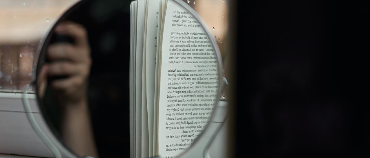 Reflet d'une main et d'un livre dans un miroir de table.