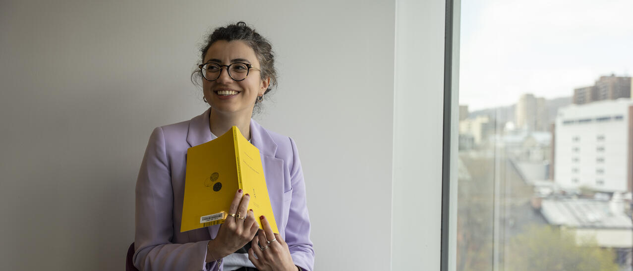 Jeune femme souriante tenant un livre.