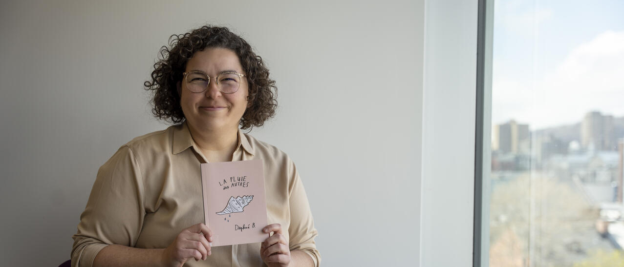 Jeune femme souriante tenant le livre La pluie des autres, de Daphné B.