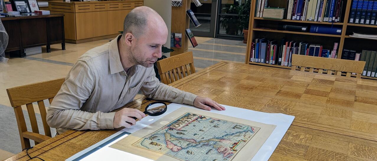 Photographie d’Alban Berson, examinant une carte géographique