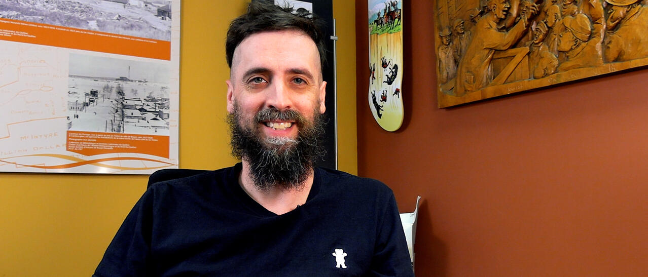 Portrait d'un homme barbu et souriant.