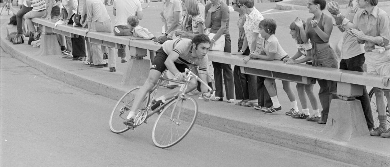 Coureur cycliste négociant un virage, devant une foule de spectateurs.