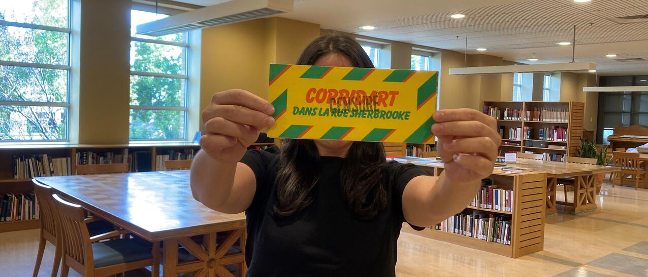Une femme tient une affiche sur laquelle est inscrit "Corridart" devant ses yeux